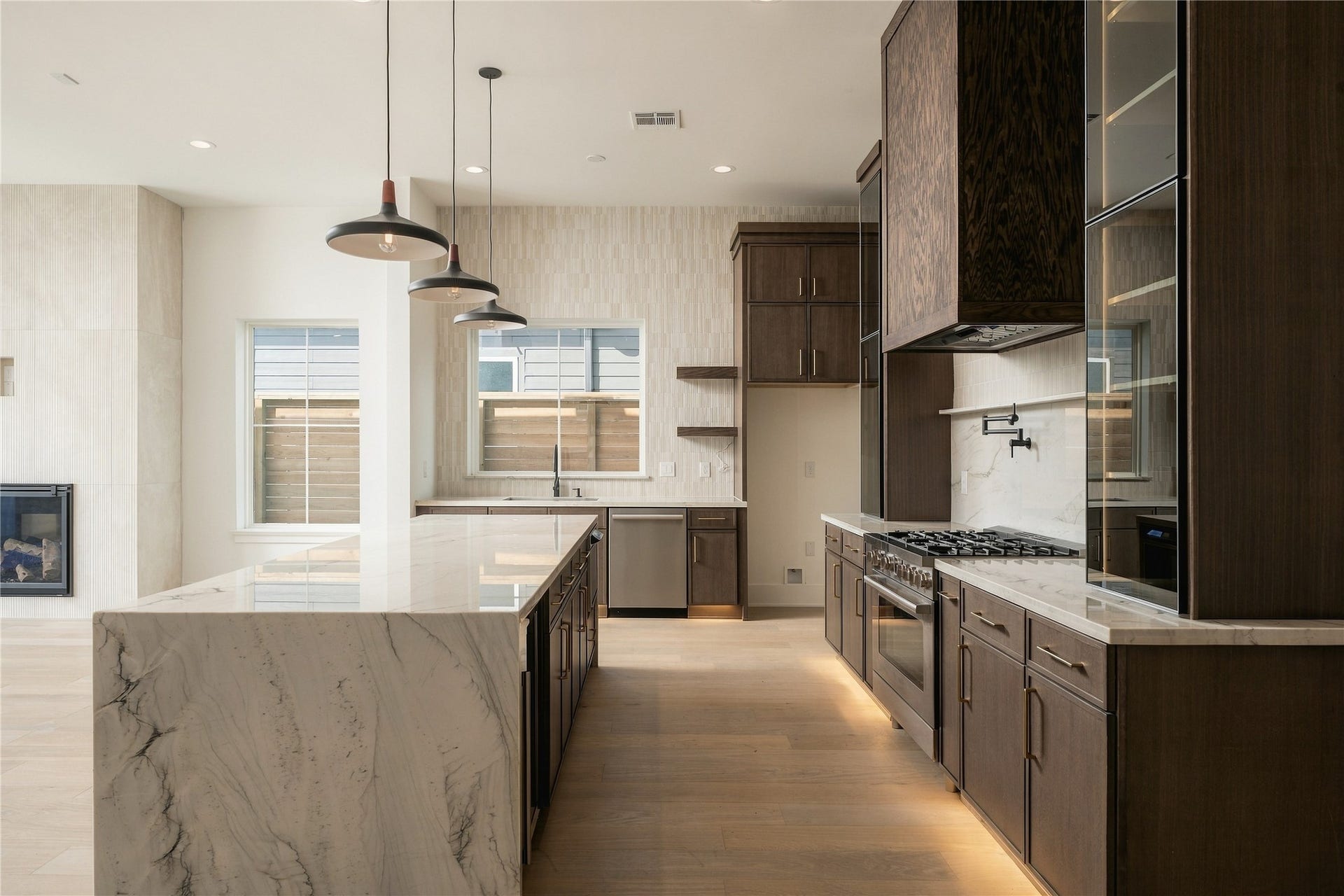 2107 McKean Drive, Houston, TX 77080 Custom Midnight Glass Towers frame the Bosch range, complemented by a white oak vent hood and illuminated cabinetry that gives the kitchen a distinctly tailored, furniture-like quality.