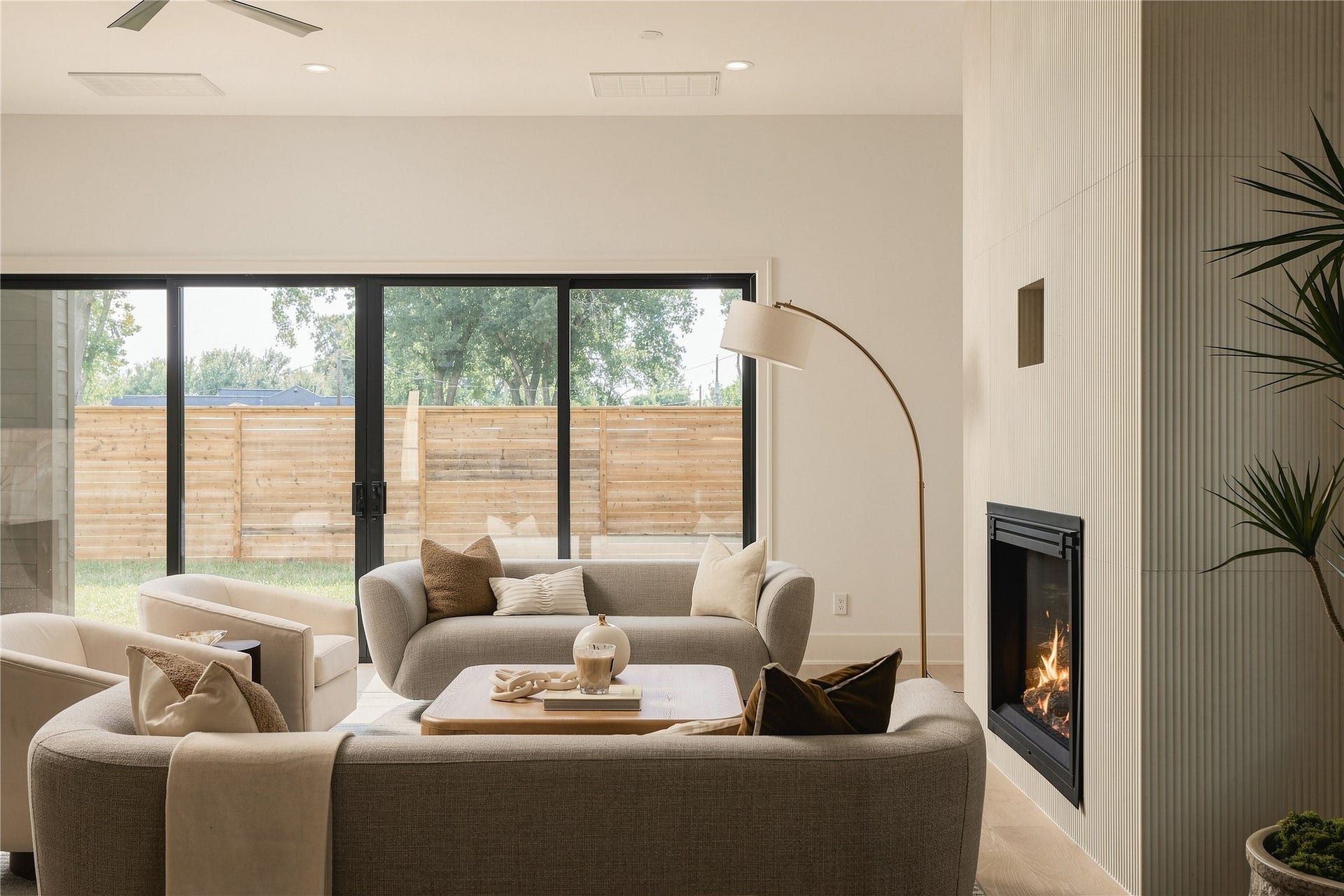 2107 McKean Drive, Houston, TX 77080 Expansive sliding glass doors frame views of the private backyard, filling the living room with natural light. A floor-to-ceiling textured fireplace adds architectural character, creating a comfortable balance of warmth and contemporary design.