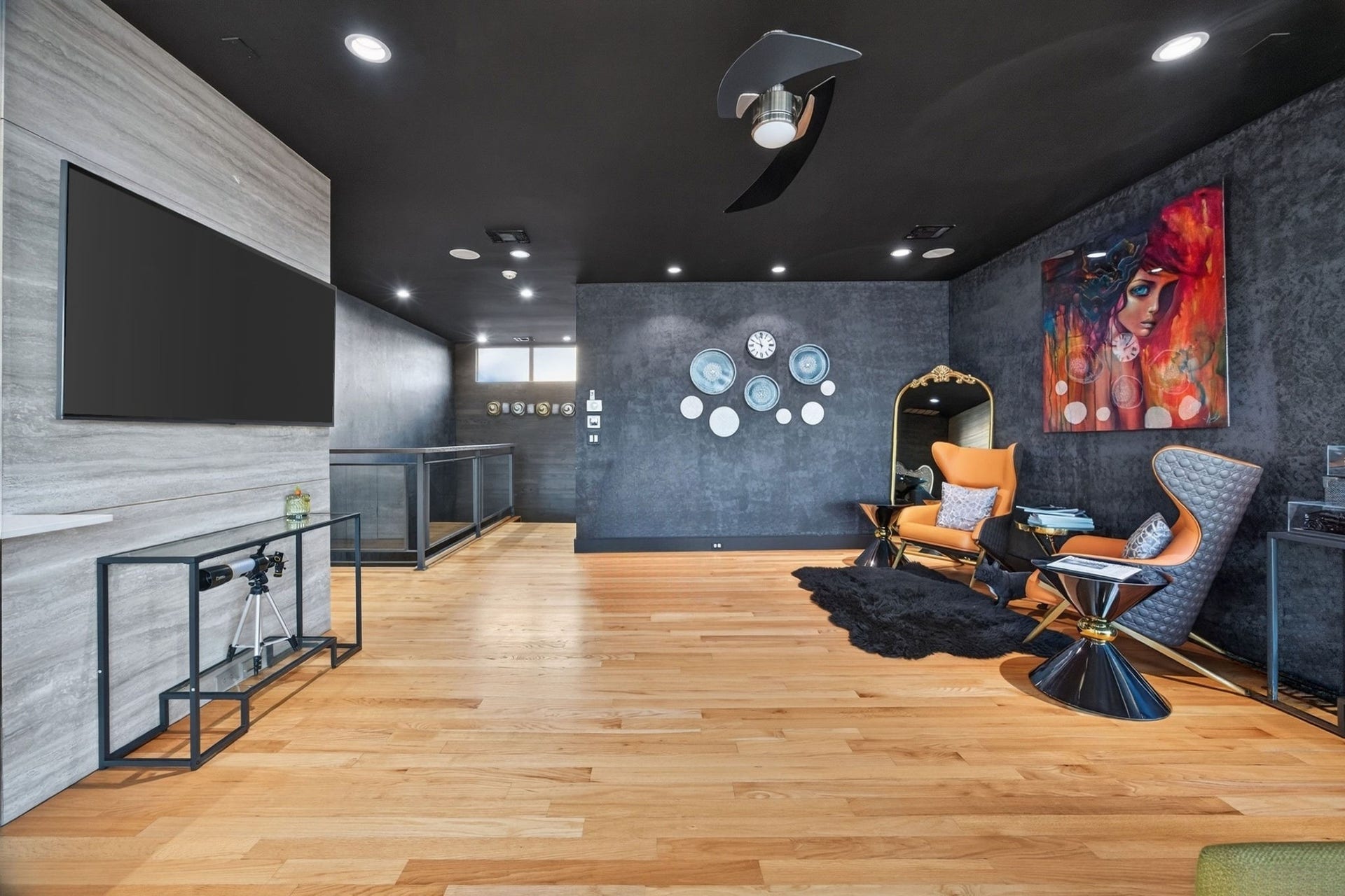 1310 Nantucket Drive, Houston, TX 77057 Stylish living area featuring sleek hardwood floors, bold artwork, and modern seating, complemented by a chic ceiling fan and ambient lighting for a contemporary vibe.