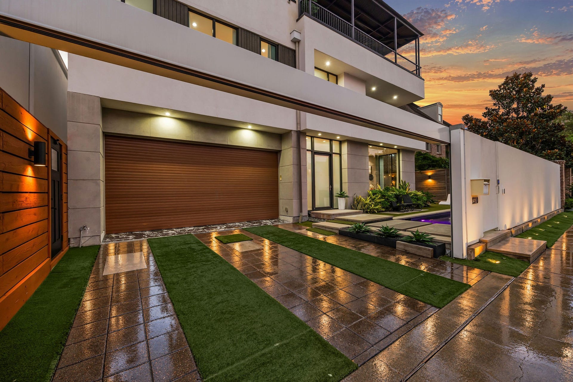 1310 Nantucket Drive, Houston, TX 77057 Modern elegance meets sophistication in this stunning home, featuring a sleek facade with a spacious garage, ambient lighting, and lush landscaping.