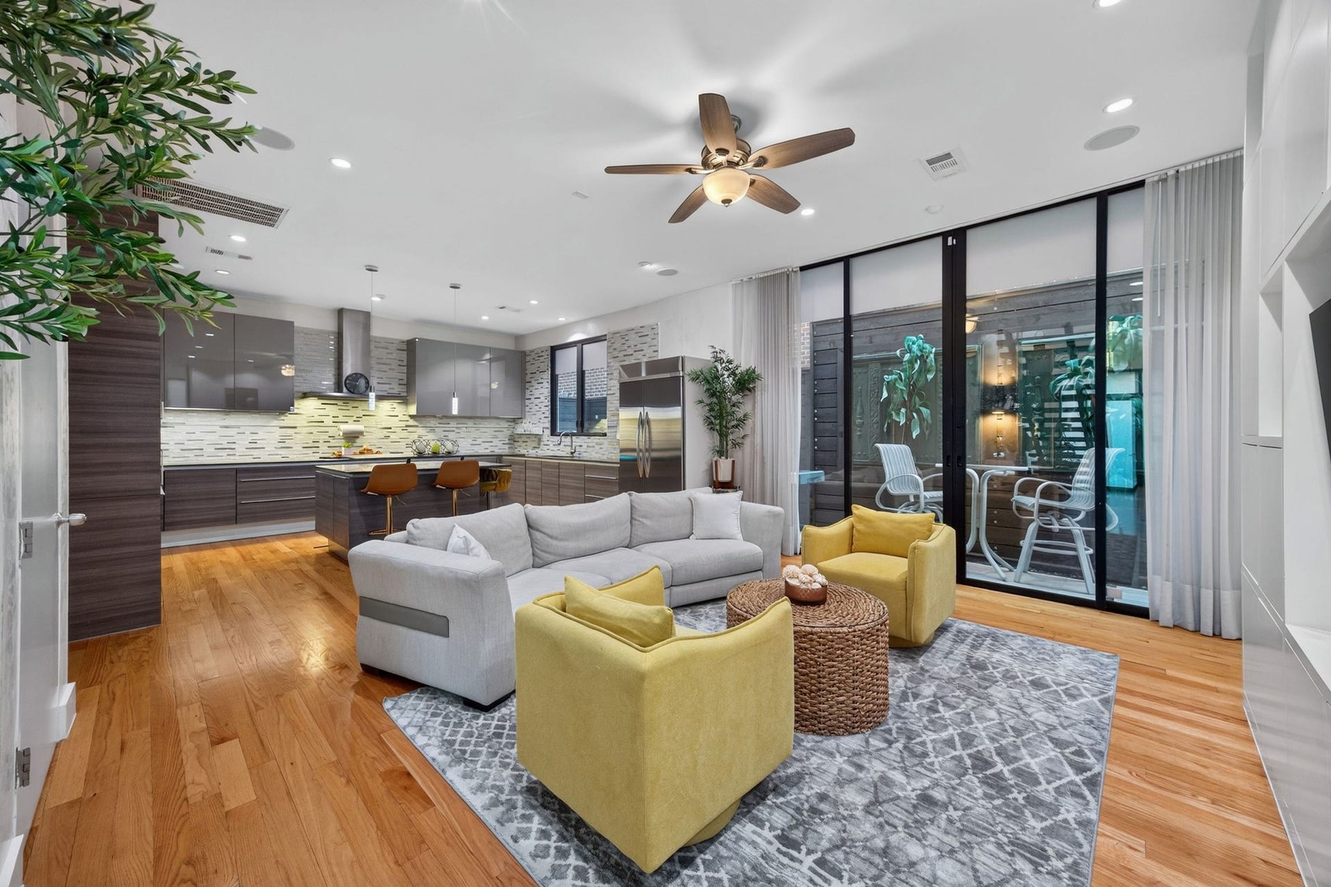 1310 Nantucket Drive, Houston, TX 77057 Spacious open-concept living area featuring a modern kitchen with sleek cabinetry and a cozy living space with vibrant accents. Large windows provide ample natural light and access to a stylish outdoor patio.