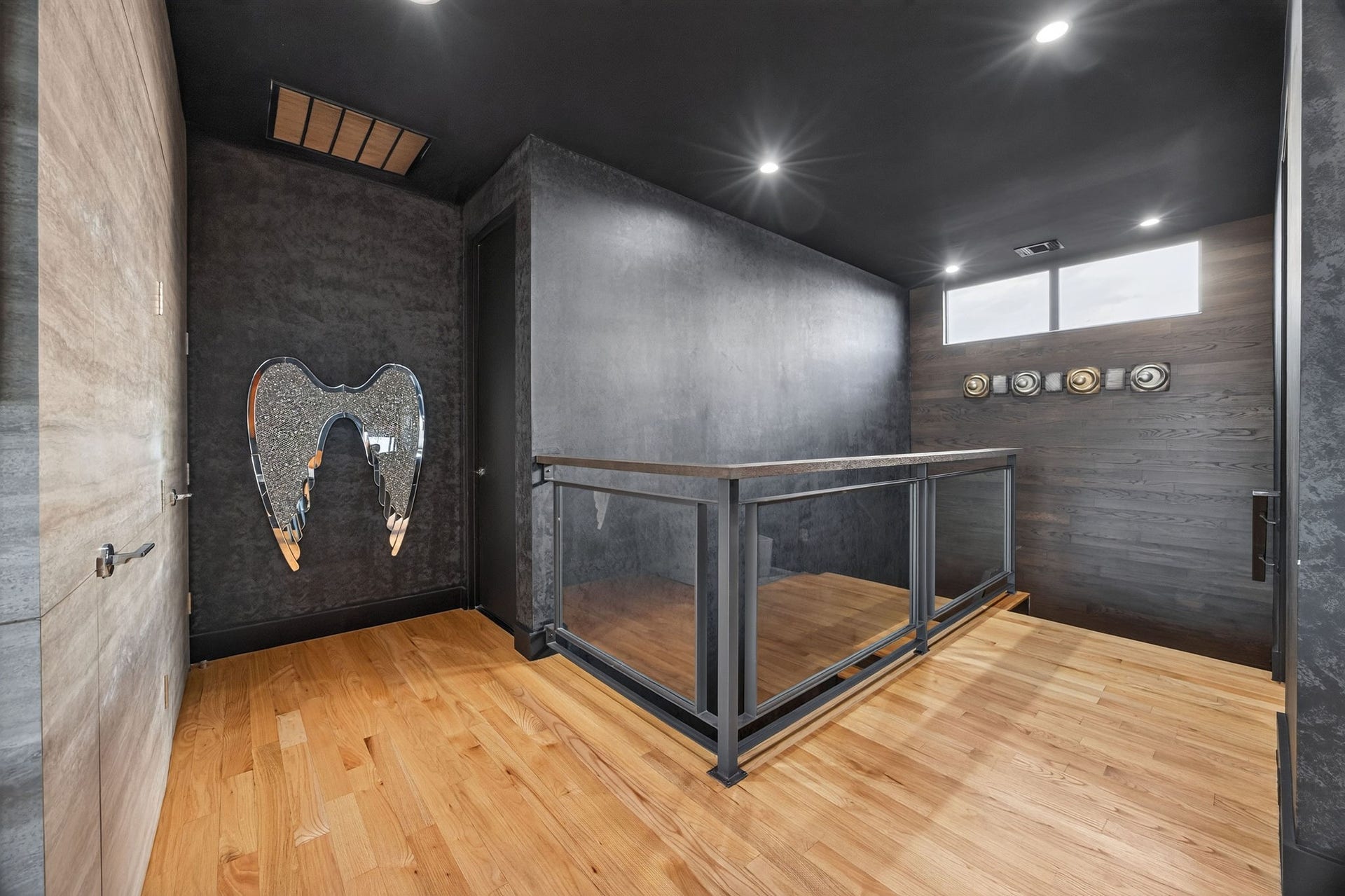 1310 Nantucket Drive, Houston, TX 77057 Contemporary landing area with sleek black walls, modern lighting, and a unique mirrored wall art piece.