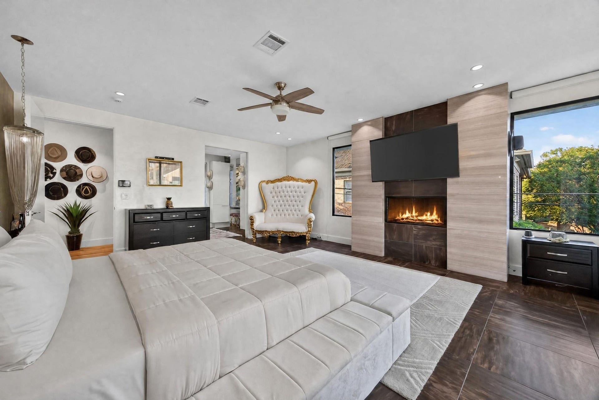 1310 Nantucket Drive, Houston, TX 77057 Luxurious bedroom featuring a cozy fireplace, elegant seating, and expansive windows offering serene views, complemented by tasteful decor and modern finishes.