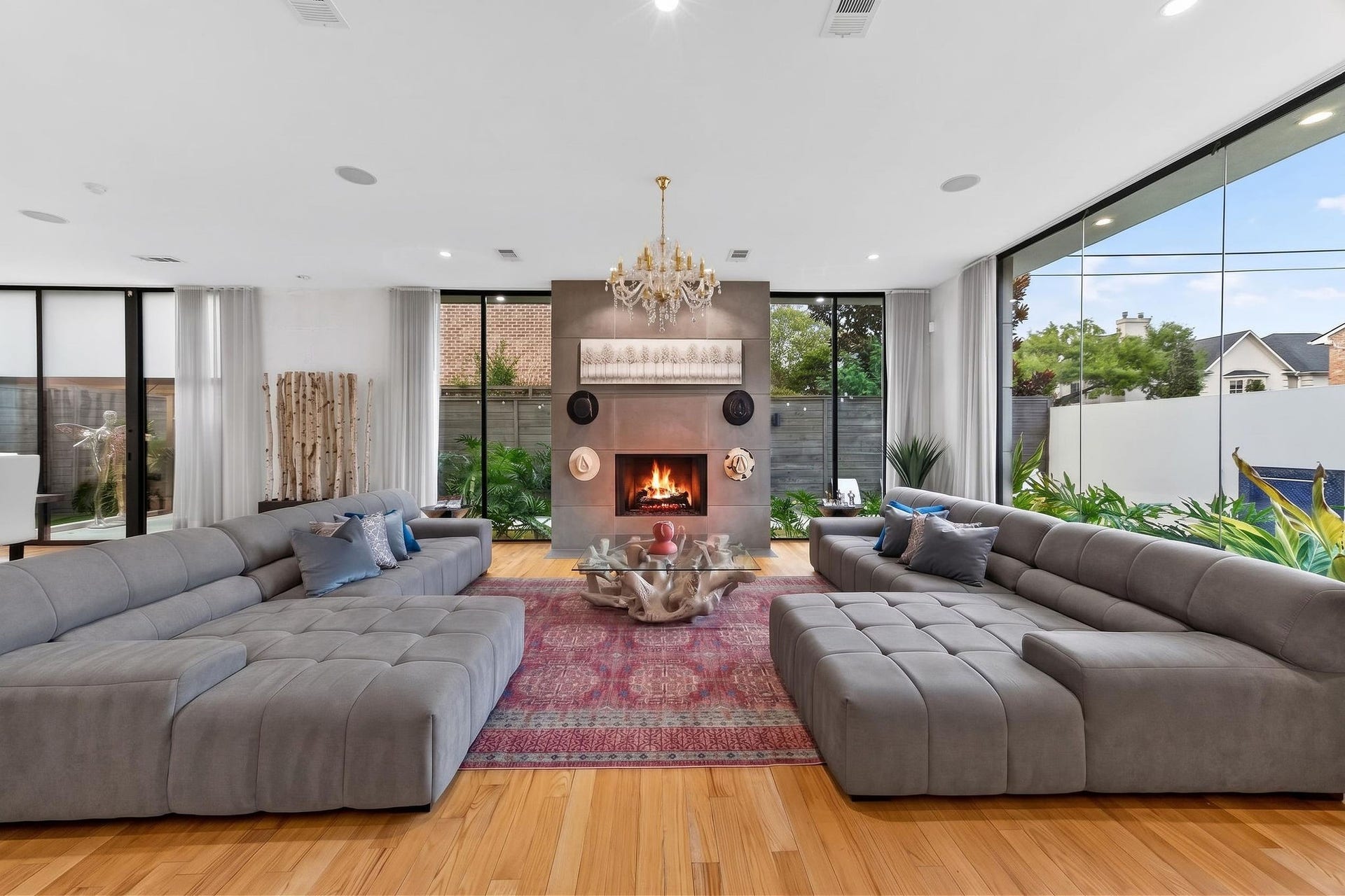1310 Nantucket Drive, Houston, TX 77057 Spacious and elegant living area with floor-to-ceiling windows offering abundant natural light, a modern fireplace, and plush sectional seating, perfect for relaxation and entertaining.