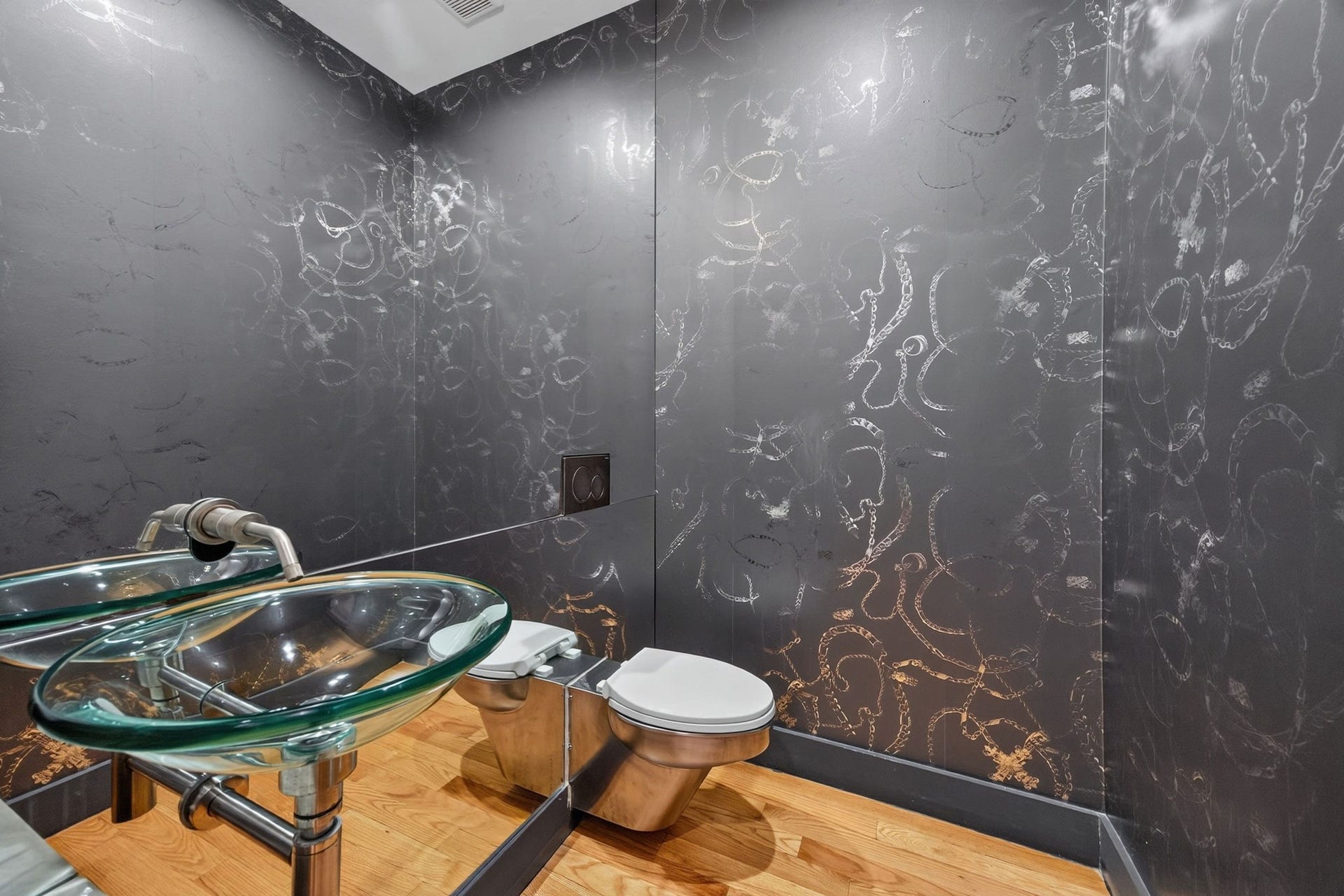 1310 Nantucket Drive, Houston, TX 77057 Chic half-bathroom with modern fixtures, featuring a unique glass vessel sink and sleek metallic wall accents.