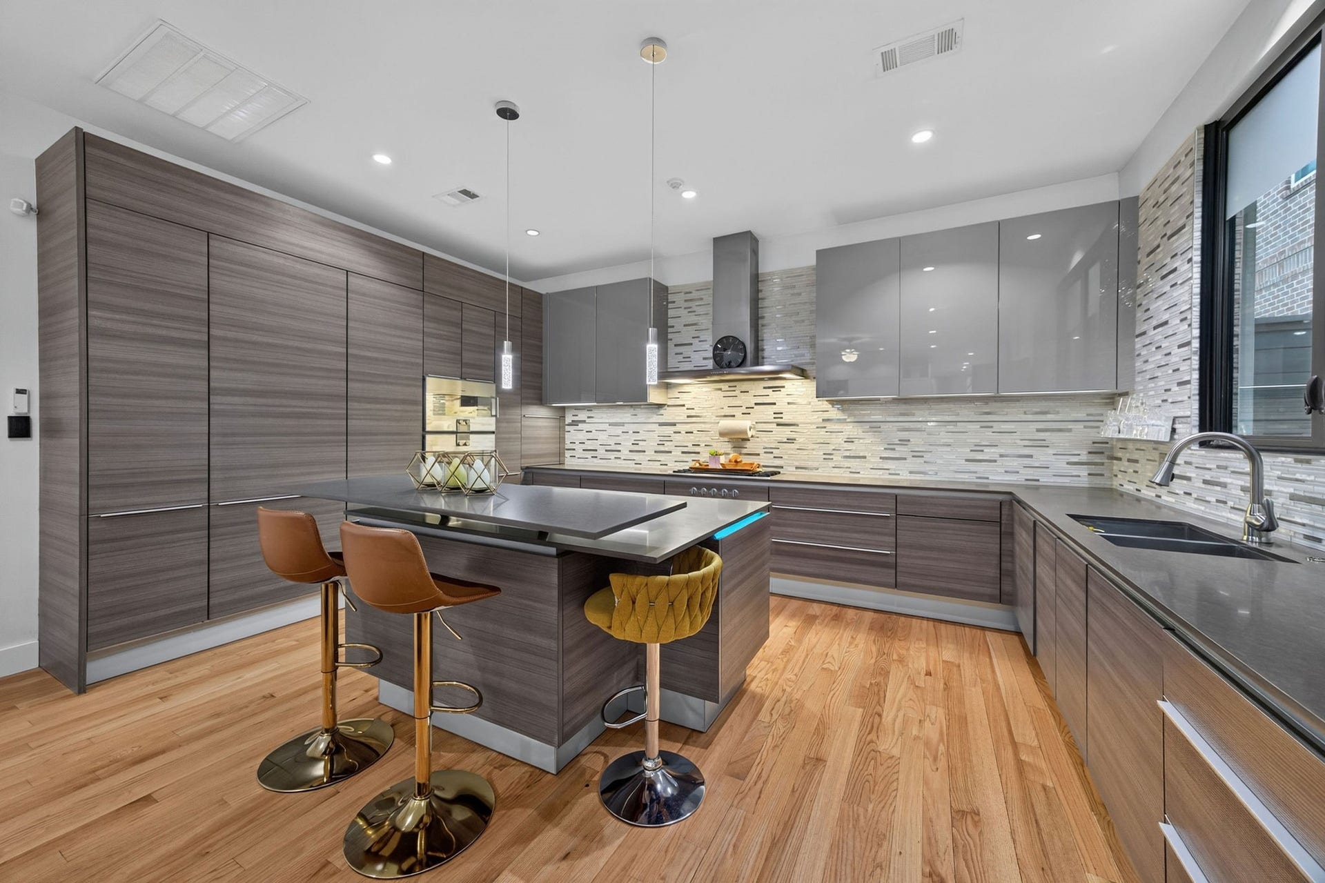 1310 Nantucket Drive, Houston, TX 77057 Sleek modern kitchen with custom cabinetry, high-end appliances, and a spacious island featuring stylish bar seating.