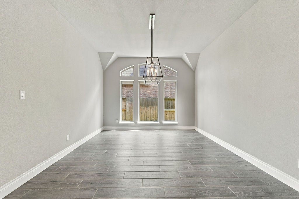 6914 Red Oak Drive, Katy, TX 77493 Bright and spacious room featuring large windows, sleek gray flooring, and a modern chandelier, perfect for dining or living.