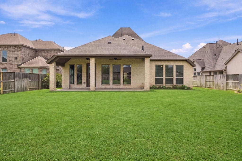 6914 Red Oak Drive, Katy, TX 77493 Spacious backyard featuring a covered patio, perfect for outdoor relaxation and entertaining, with a well-maintained lawn and privacy fencing.