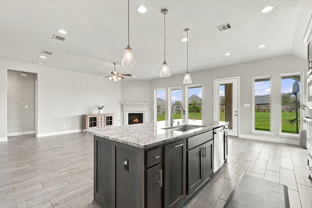 6914 Red Oak Drive, Katy, TX 77493 Spacious open-concept living area with a modern kitchen island, elegant pendant lighting, and large windows offering abundant natural light and views of the lush backyard.