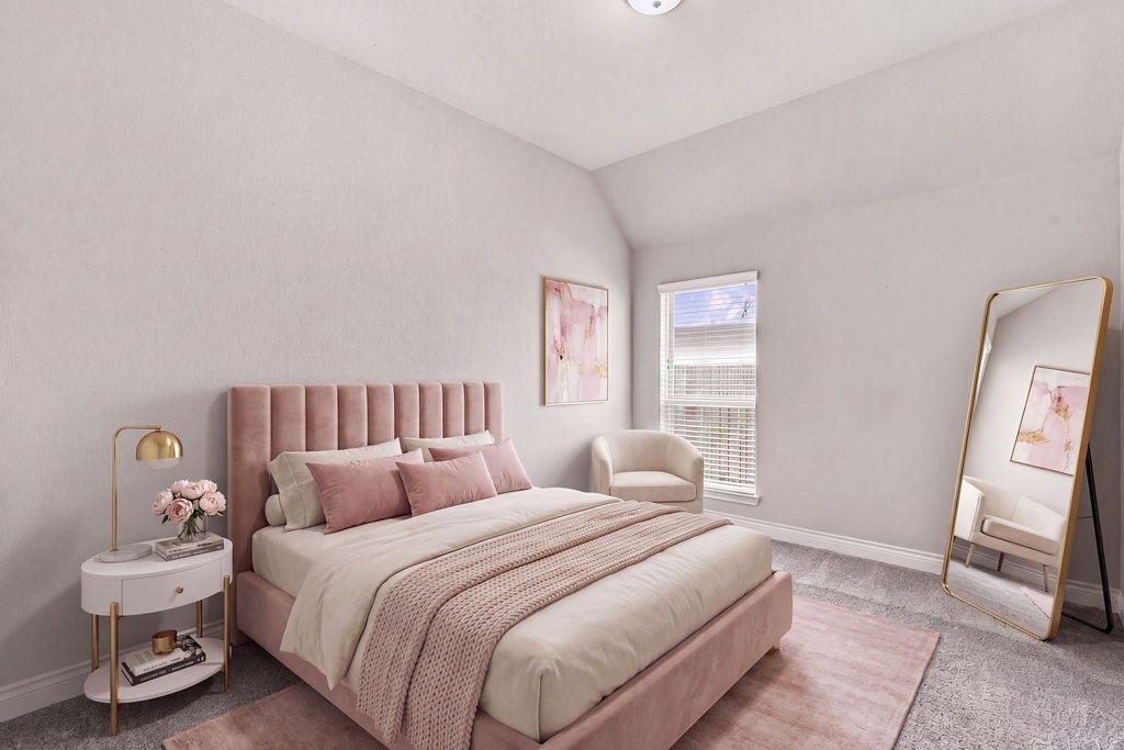 6914 Red Oak Drive, Katy, TX 77493 Cozy bedroom with soft pink accents, featuring a plush bed, elegant side table, and stylish full-length mirror. Abundant natural light streams through the window, enhancing the serene atmosphere.