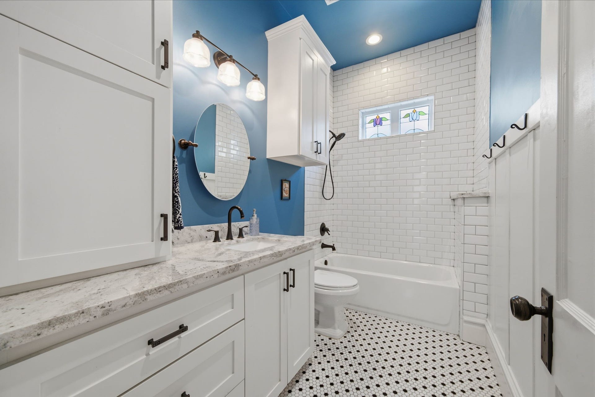 Guest bathroom (tub/shower combo) located between the 2 guest bedrooms at front of the home. Plenty of storage and gorgeous stained glass windows - letting in natural light, whilst maintaining privacy! Subway tile all the way to the ceiling in here too! Note the wainscoting feature (on the right) adding a little more charm to this guest bath!