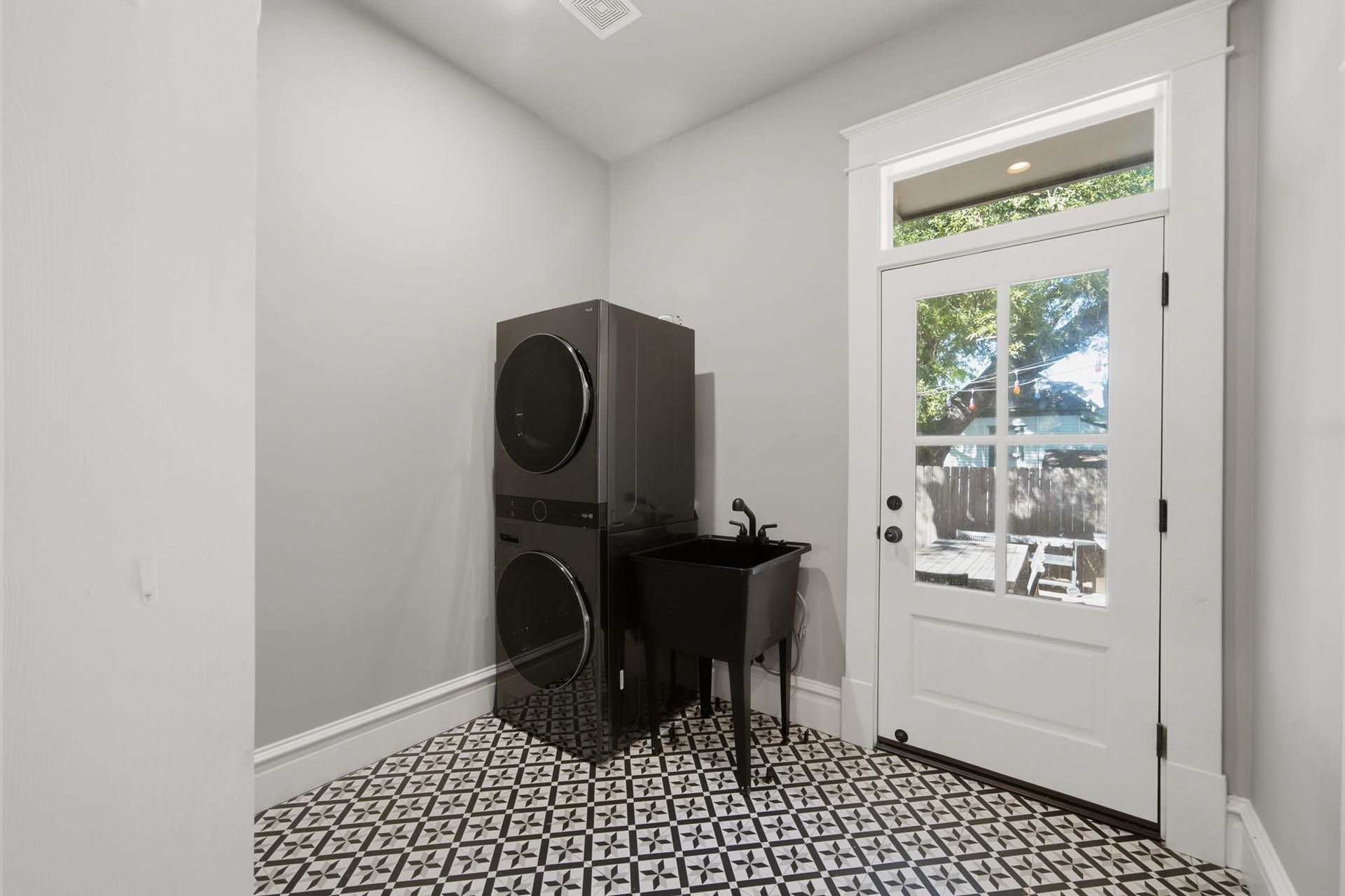Laundry/mudroom just off the kitchen. NEW (2026) washer/dryer in the corner. Utility sink and lots of shelves (not in this picture) for storage. Whimsical floor tile! Door leads out into the BACKYARD!