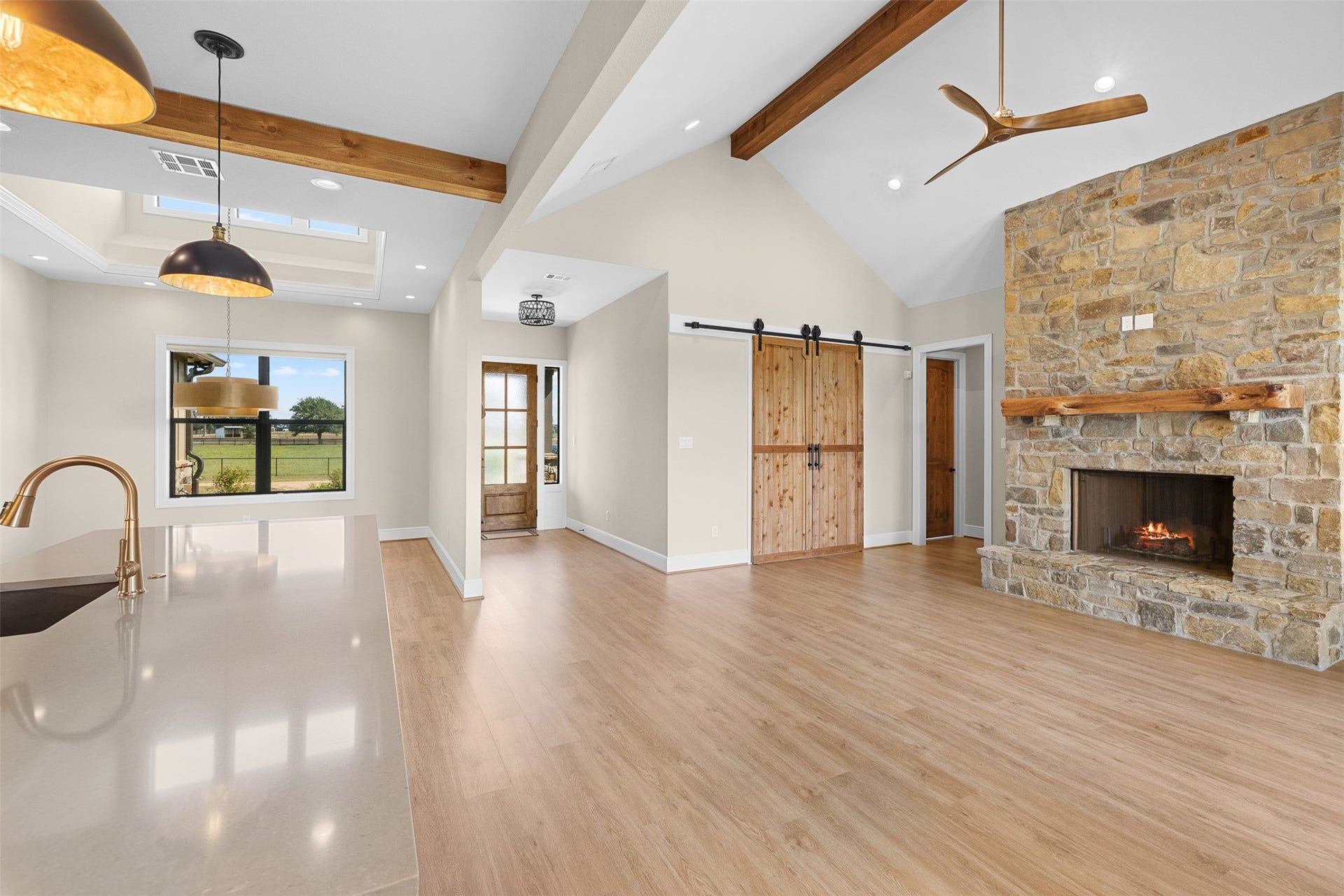 30163 High Spirit Ranch Road, Hempstead, TX 77445 Another view of the main living space. Barn doors accent the study entrance. Formal dining space off the kitchen with custom lighting offers easy entertaining. Wooden beams offer farmhouse accents and character to this very comfortable living room space.