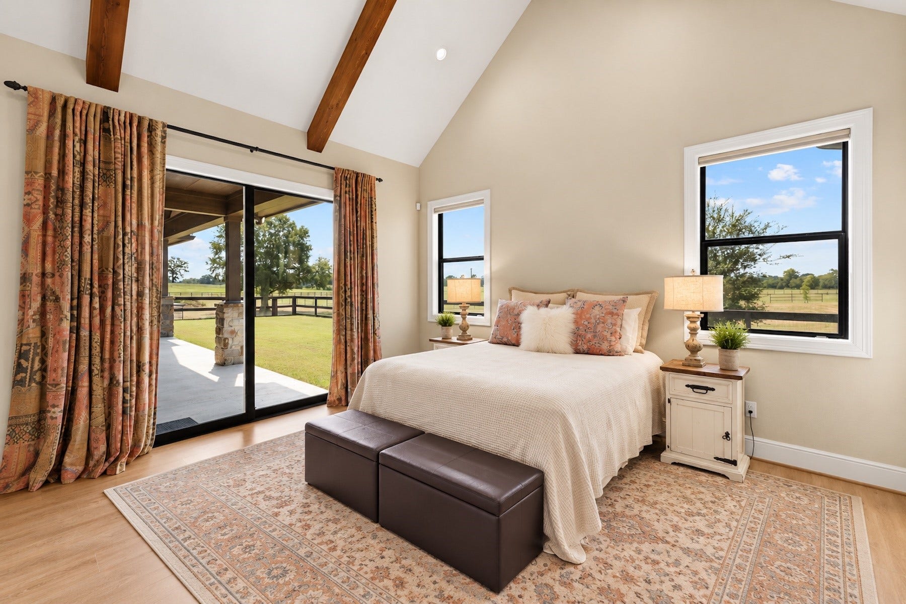 30163 High Spirit Ranch Road, Hempstead, TX 77445 Primary suite offers vaulted ceilings with wood-beamed accents, patio access through the sliding doors, and unreal views of the 11.55 acres.