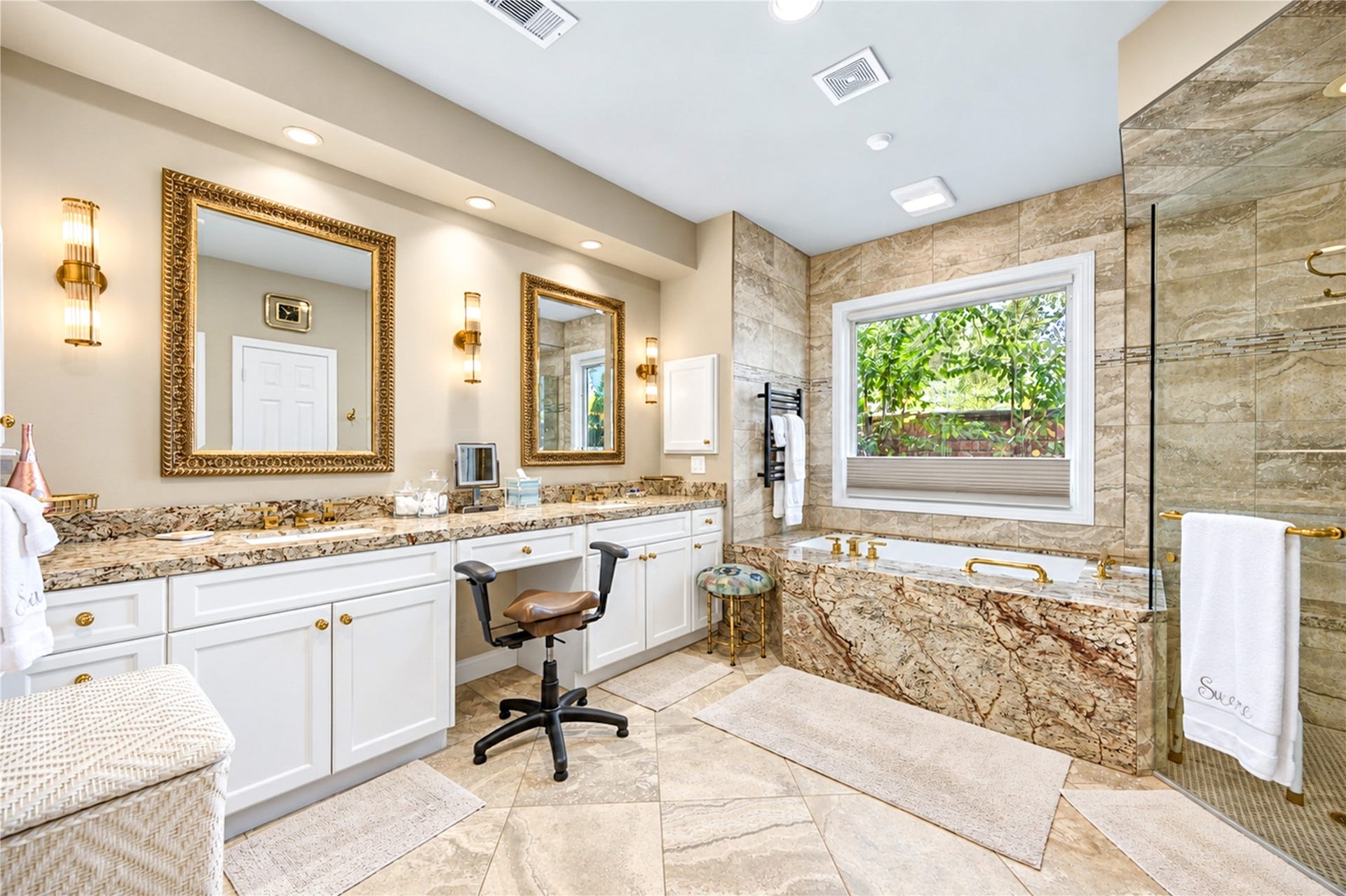 4 Milan Estates, Houston, TX 77056 Dual sinks, granite countertops and a built-in vanity seating area complete the primary bath beneath gold-framed mirrors.