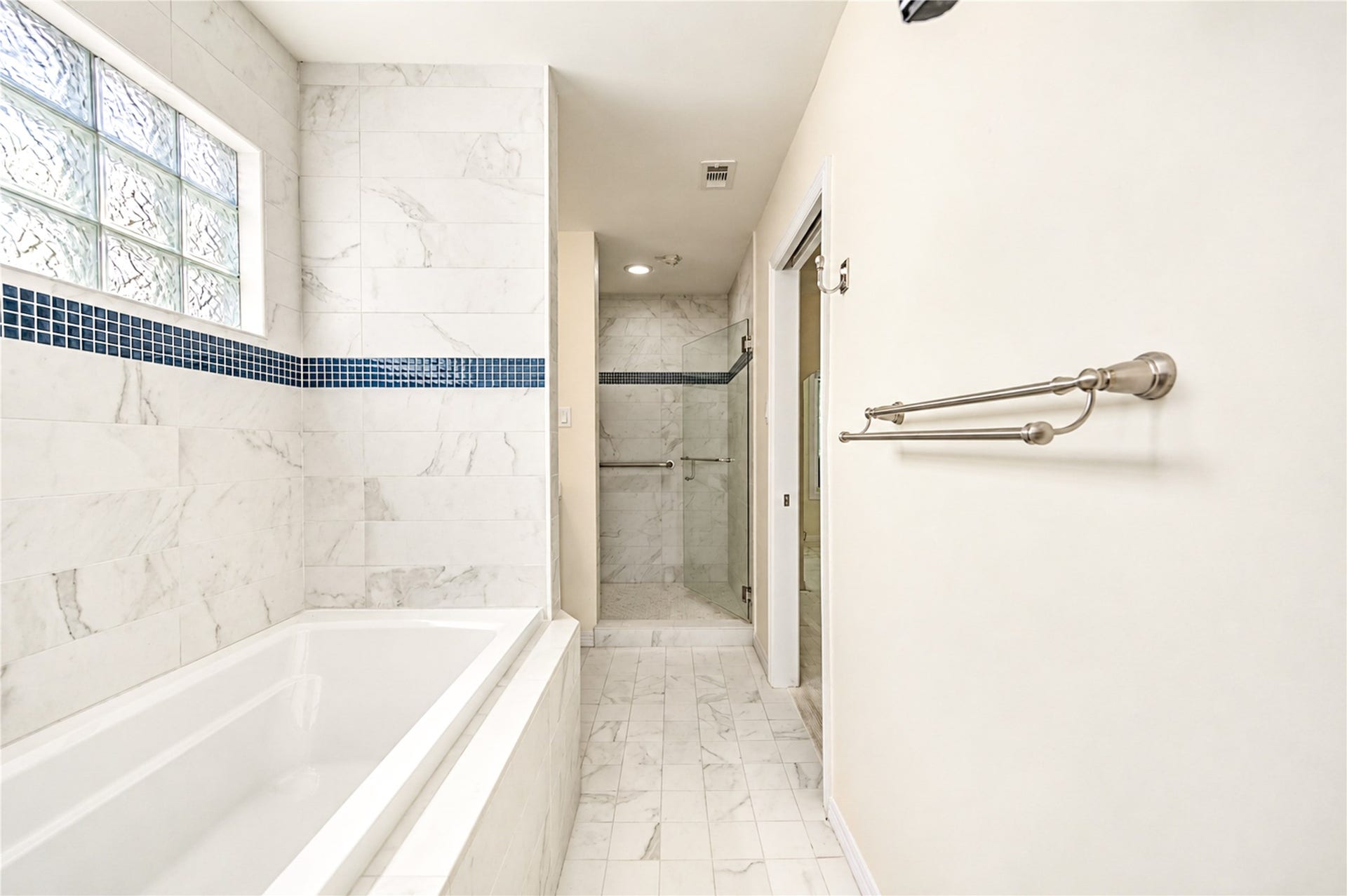 4 Milan Estates, Houston, TX 77056 A soaking tub and a glass-enclosed shower are set against marble-look tile and a glass-block window in this third-floor bath.