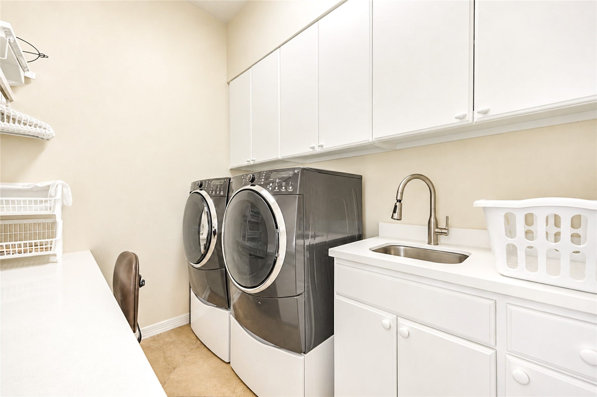 4 Milan Estates, Houston, TX 77056 The second-floor laundry room is fitted with generous upper cabinetry, a sink with a gooseneck faucet and a built-in work counter.