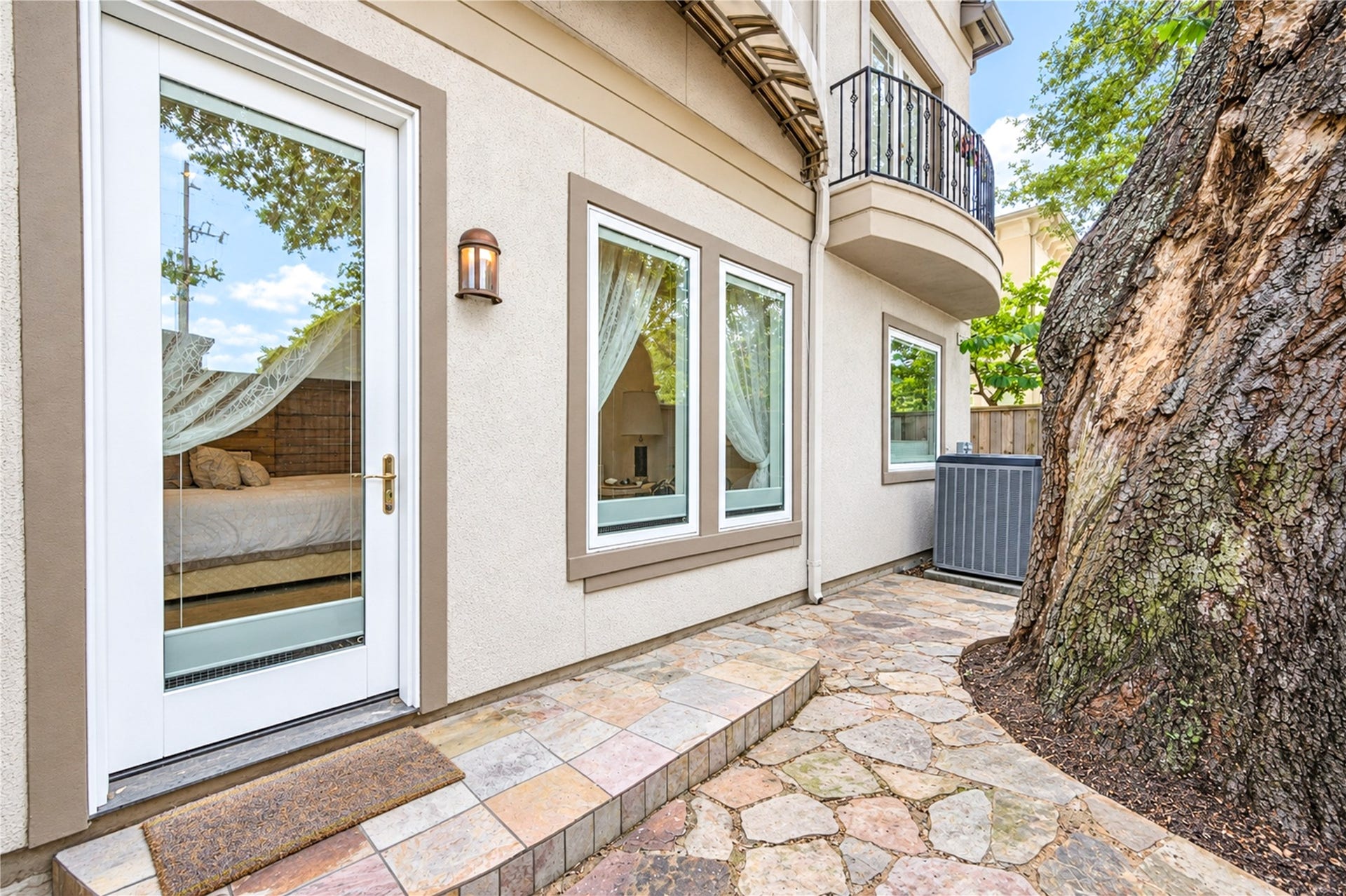 4 Milan Estates, Houston, TX 77056 Flagstone paving leads past a mature oak to a glass-paneled door at the side of the home, with a balcony above.