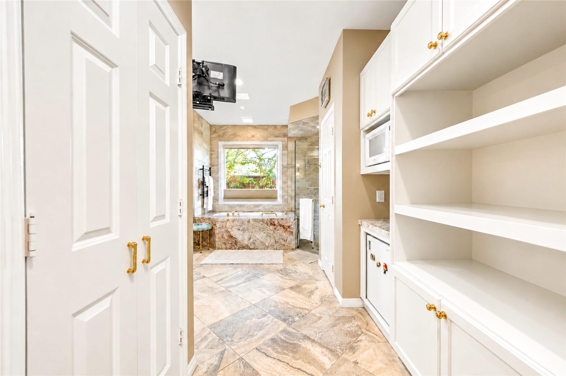 4 Milan Estates, Houston, TX 77056 A dressing corridor lined with custom built-in shelving and cabinetry leads from the first-floor primary bedroom toward the primary bath.