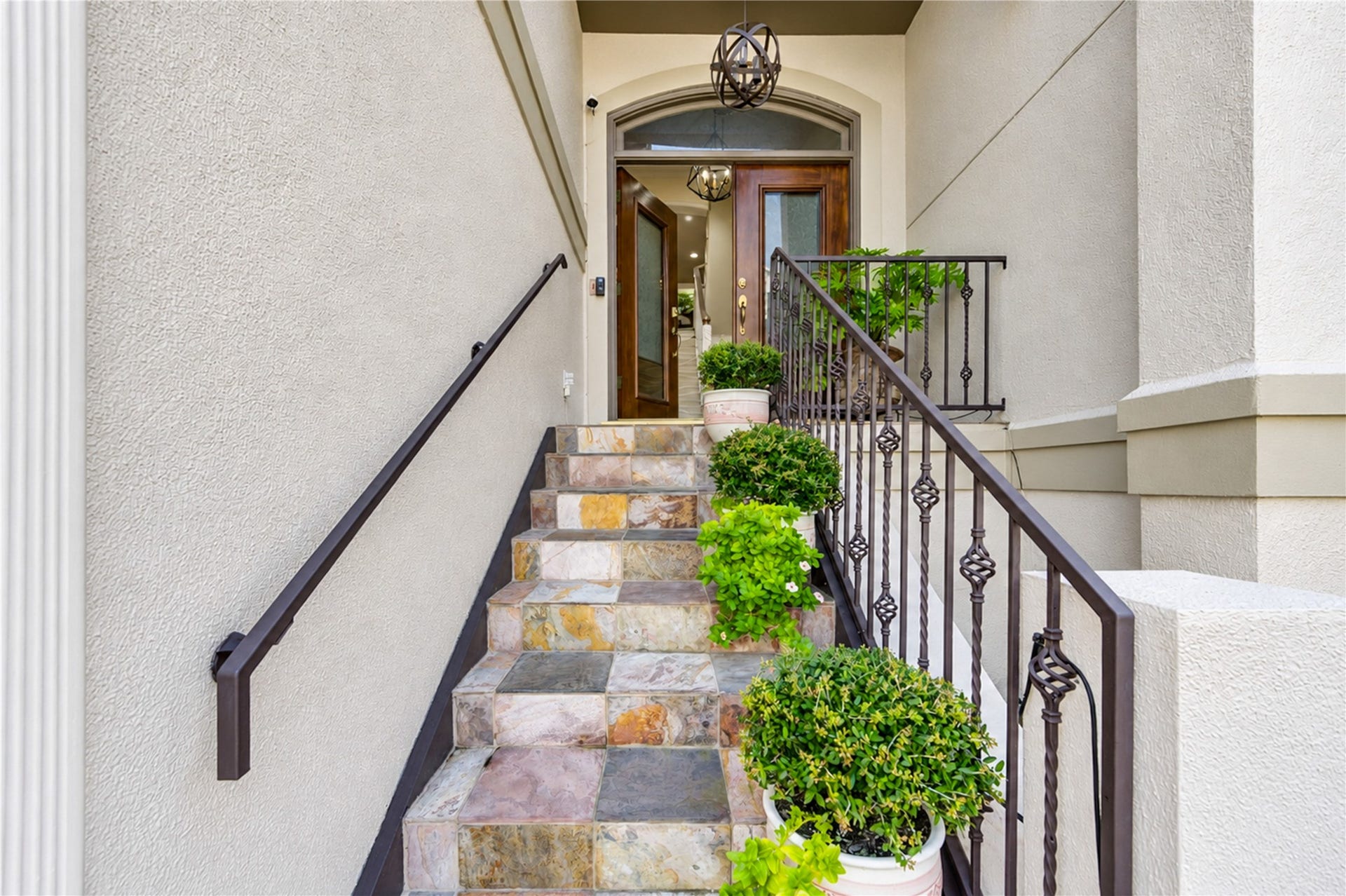 4 Milan Estates, Houston, TX 77056 A slate-clad stair with a wrought-iron railing and lush plantings leads to the arched, glass-paneled front door.