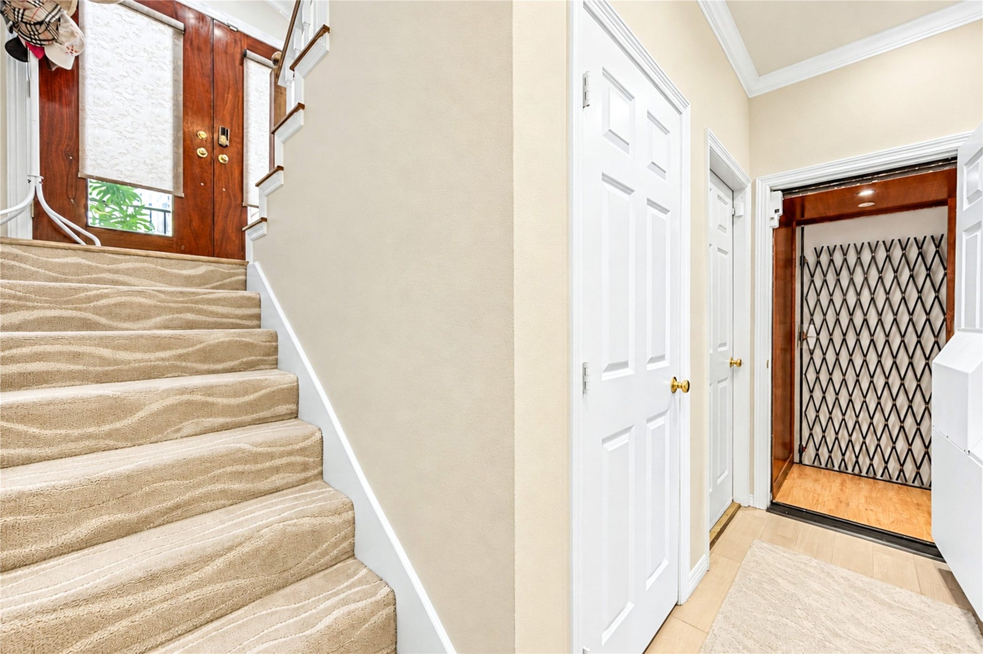 4 Milan Estates, Houston, TX 77056 Carpeted stairs lead up from the entry, with the elevator and the wood front door nearby.