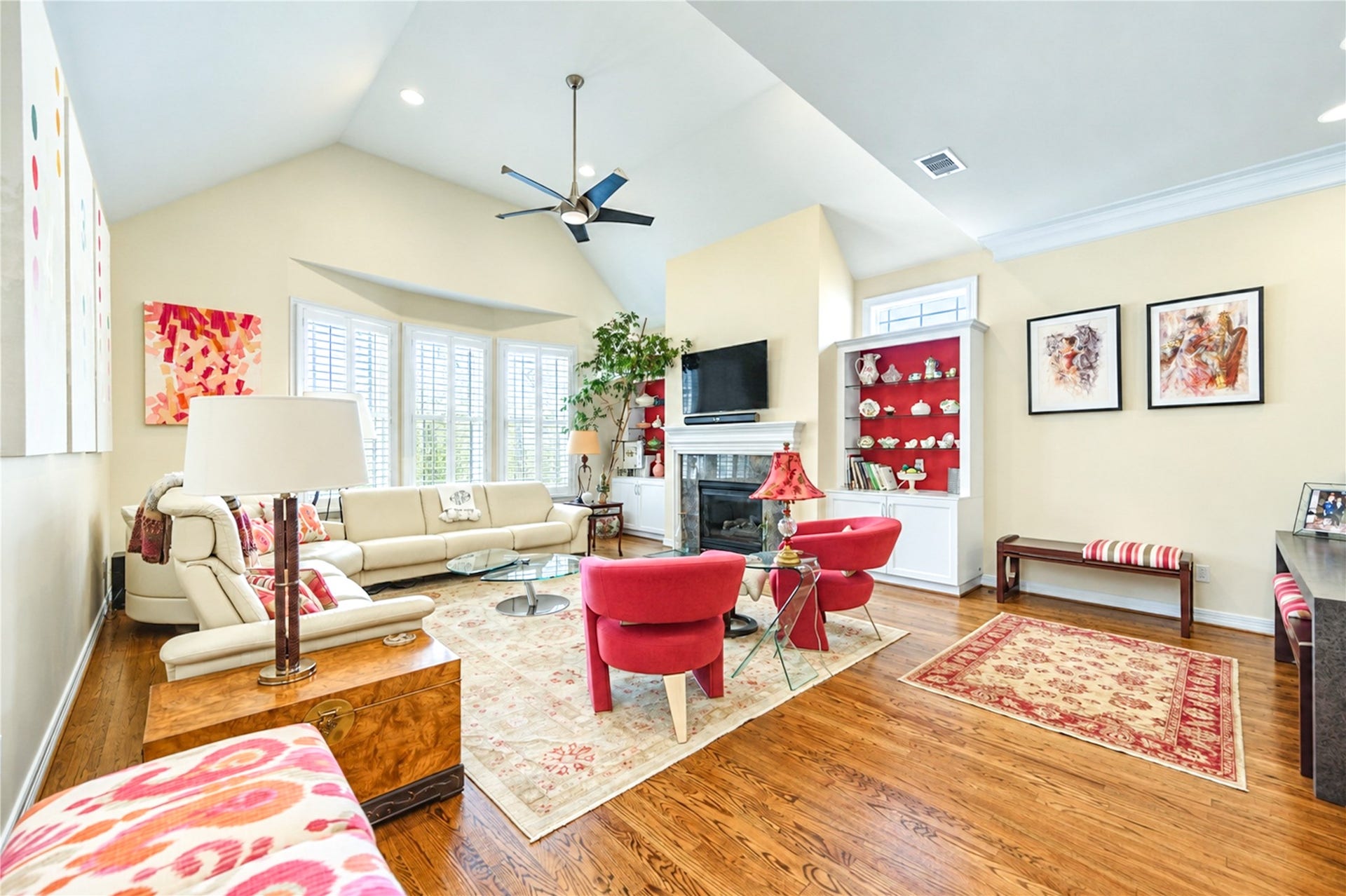 4 Milan Estates, Houston, TX 77056 The vaulted second-floor living room pairs hardwood floors with a gas-log fireplace, custom built-in display cabinetry and a bank of shuttered windows.