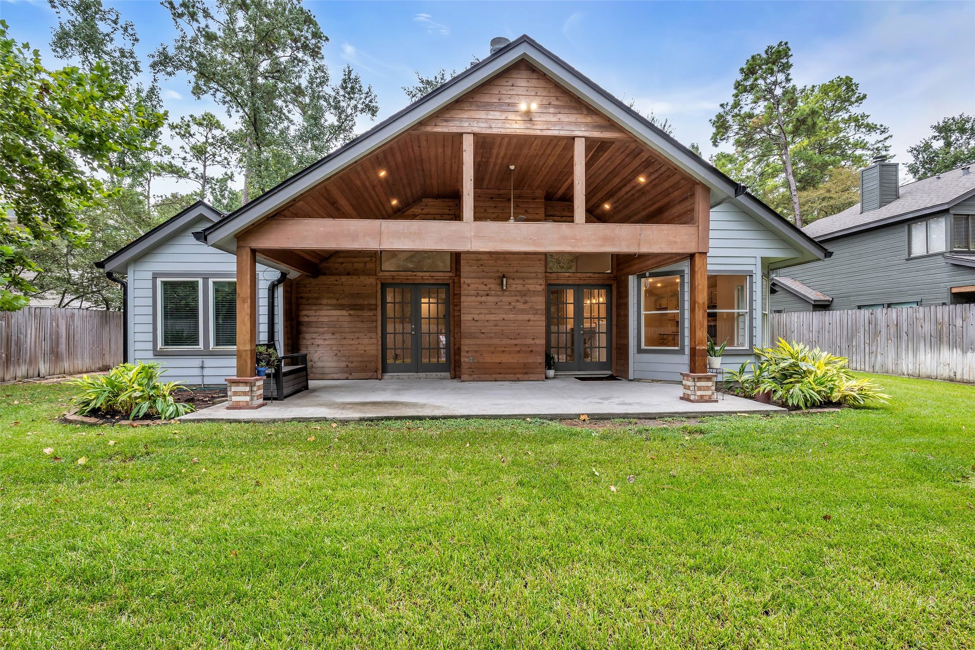 54 Sky Terrace Place, The Woodlands, TX 77381 Covered patio featuring beautiful wood accents, surrounded by lush greenery in a tranquil backyard setting.
