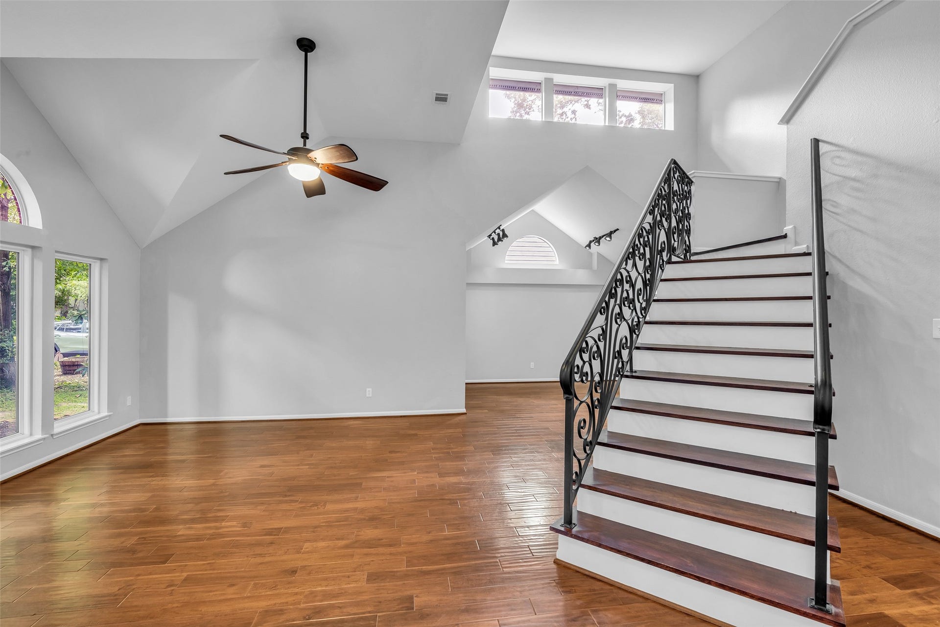 54 Sky Terrace Place, The Woodlands, TX 77381 Inviting living area showcasing beautiful hardwood floors, a distinctive wrought iron staircase, soaring ceilings, and oversized windows that bring in plenty of natural light.