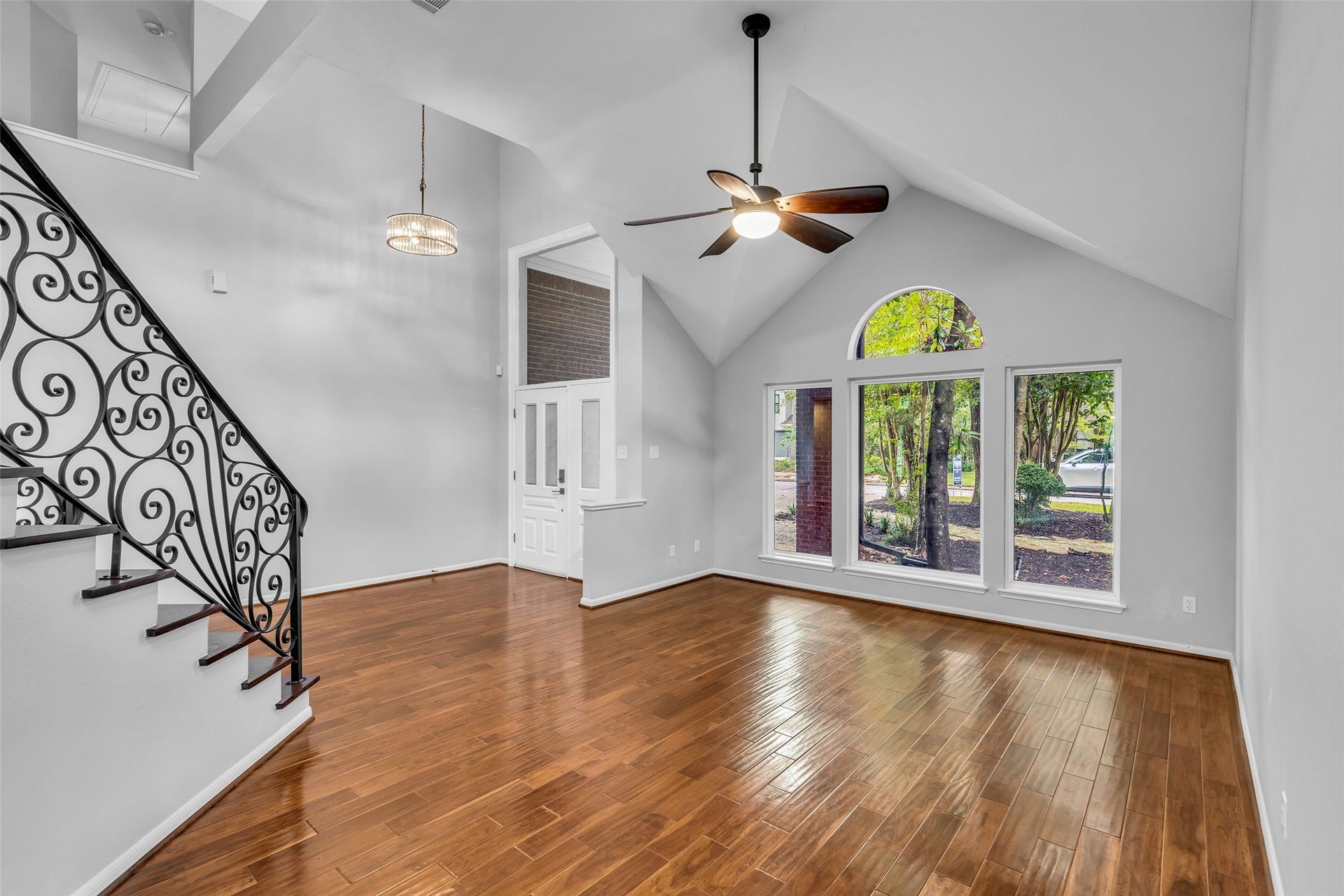54 Sky Terrace Place, The Woodlands, TX 77381 Elegant living space featuring soaring vaulted ceilings, rich hardwood floors, and large arched windows that fill the home with abundant natural light.