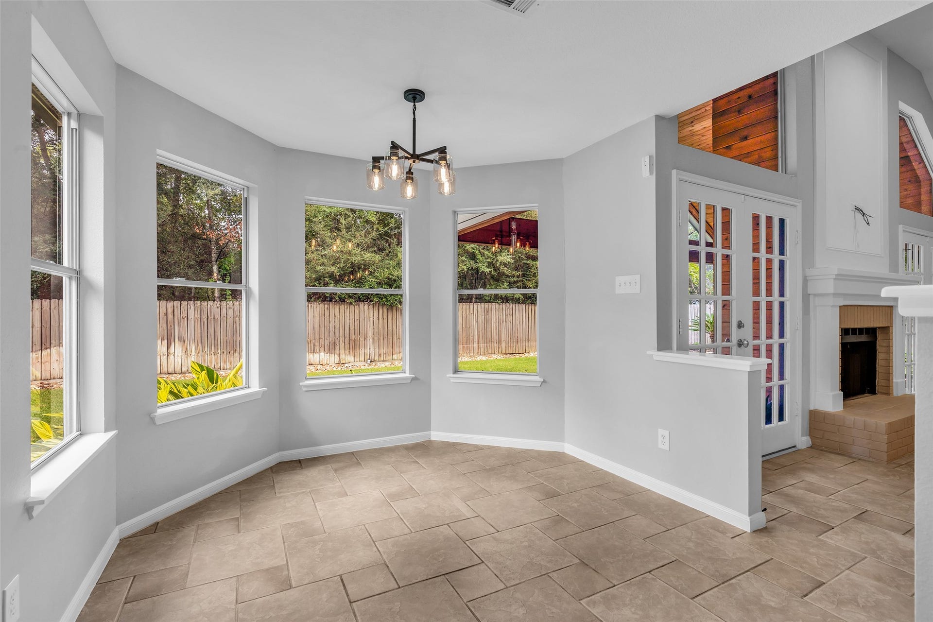 54 Sky Terrace Place, The Woodlands, TX 77381 Bright and airy breakfast nook with large windows, elegant tile flooring, and a charming chandelier, seamlessly connecting to the cozy living area with a fireplace.