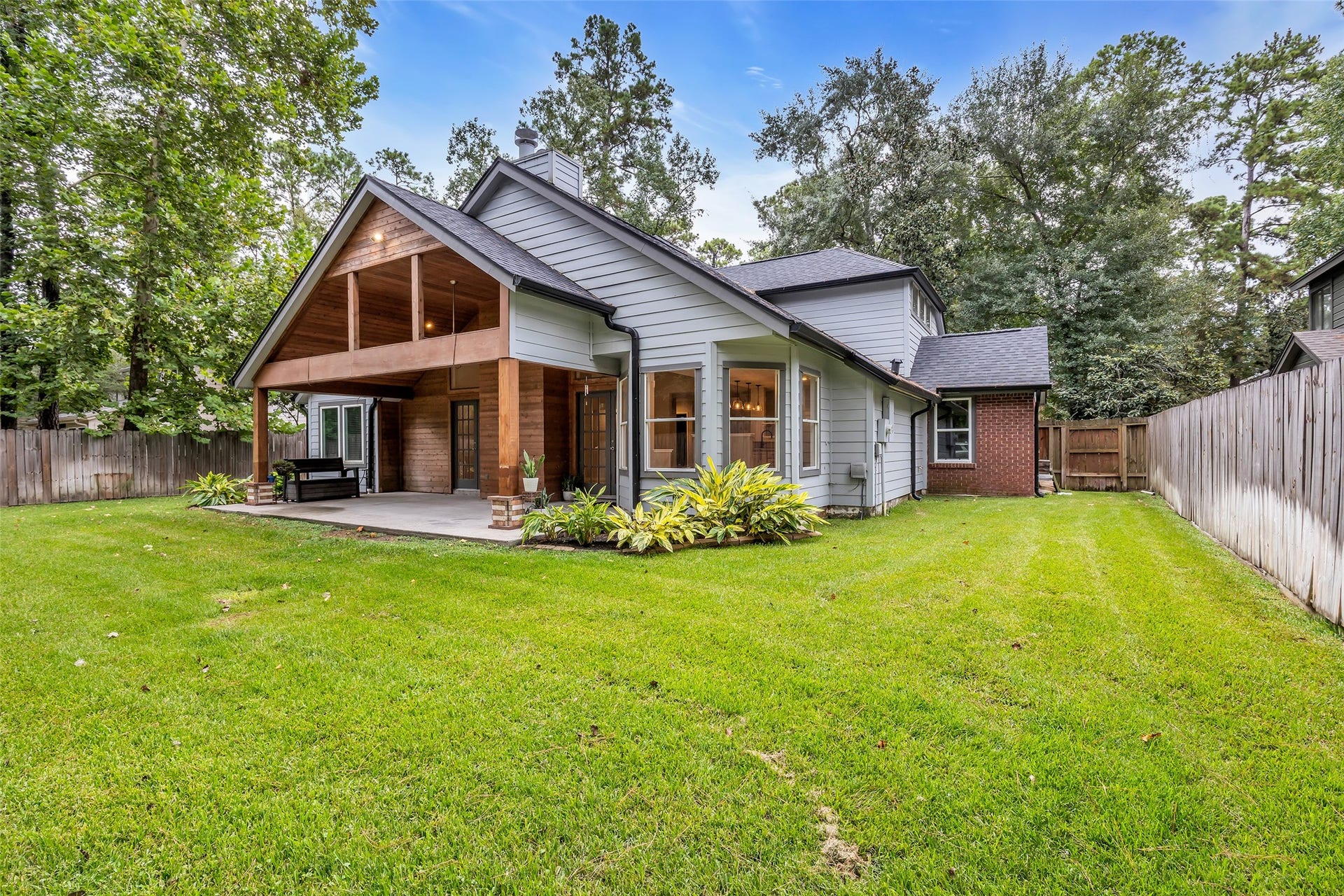 54 Sky Terrace Place, The Woodlands, TX 77381 Spacious backyard, featuring a covered patio perfect for outdoor entertaining, surrounded by lush greenery and mature trees for added privacy.