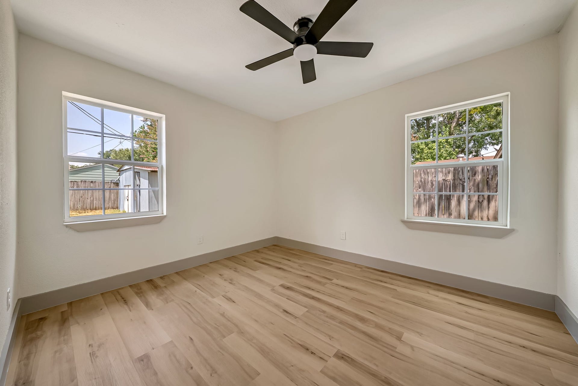 6638 Thornwall Street, Houston, TX 77092 Bright and inviting bedroom featuring large windows, sleek wood flooring, and a modern ceiling fan.