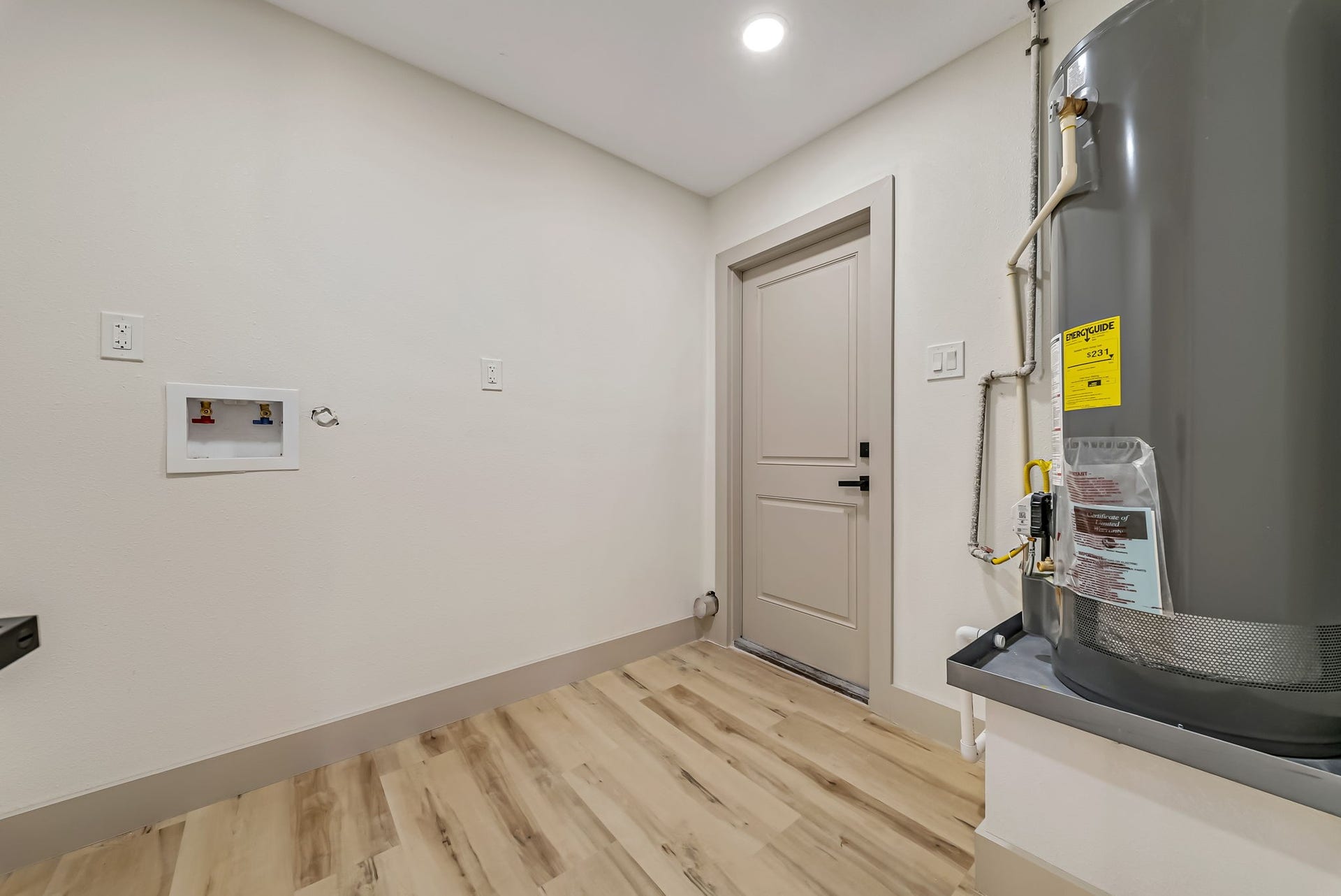 6638 Thornwall Street, Houston, TX 77092 Spacious laundry room with modern hookups, a water heater, and sleek flooring, providing functionality and style.