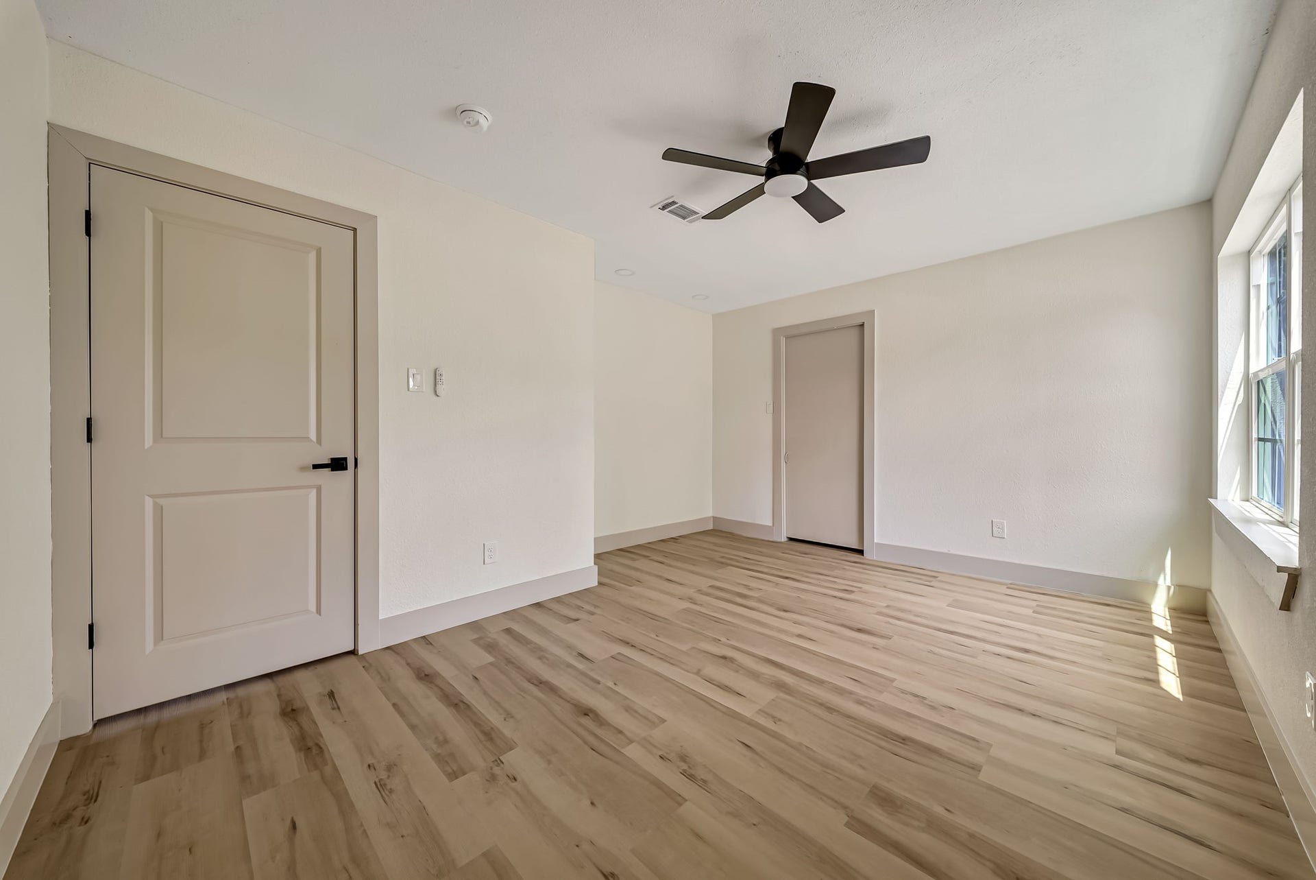6638 Thornwall Street, Houston, TX 77092 Spacious and bright room featuring sleek LVP flooring, a modern ceiling fan, and abundant natural light streaming through a large window.