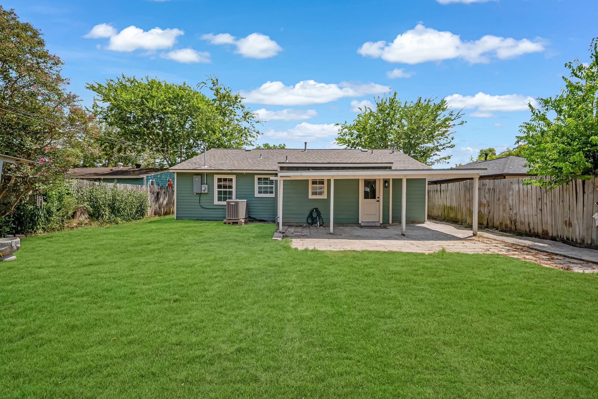 6638 Thornwall Street, Houston, TX 77092 Charming backyard with a spacious lawn, cozy covered patio, and privacy fencing, perfect for outdoor relaxation and gatherings.