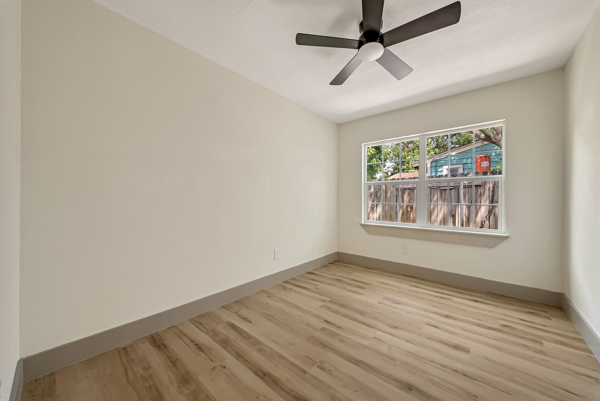 6638 Thornwall Street, Houston, TX 77092 Bright bedroom featuring a large window, sleek ceiling fan, and elegant wood flooring.