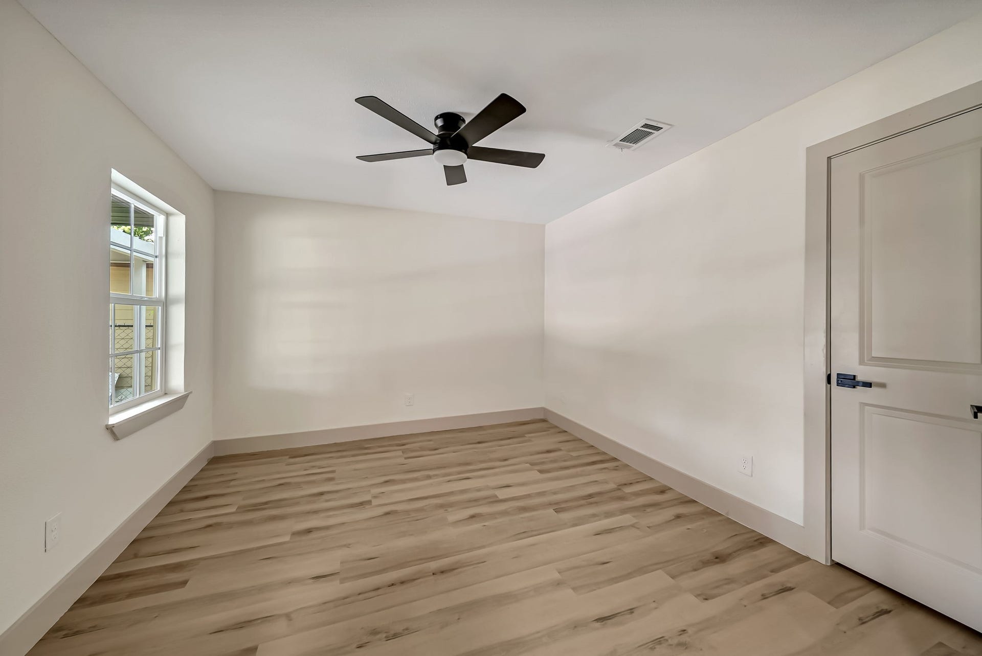 6638 Thornwall Street, Houston, TX 77092 Bright and spacious office/possible bedroom room featuring sleek wood like LVP flooring, a modern ceiling fan, and ample natural light from a large window.