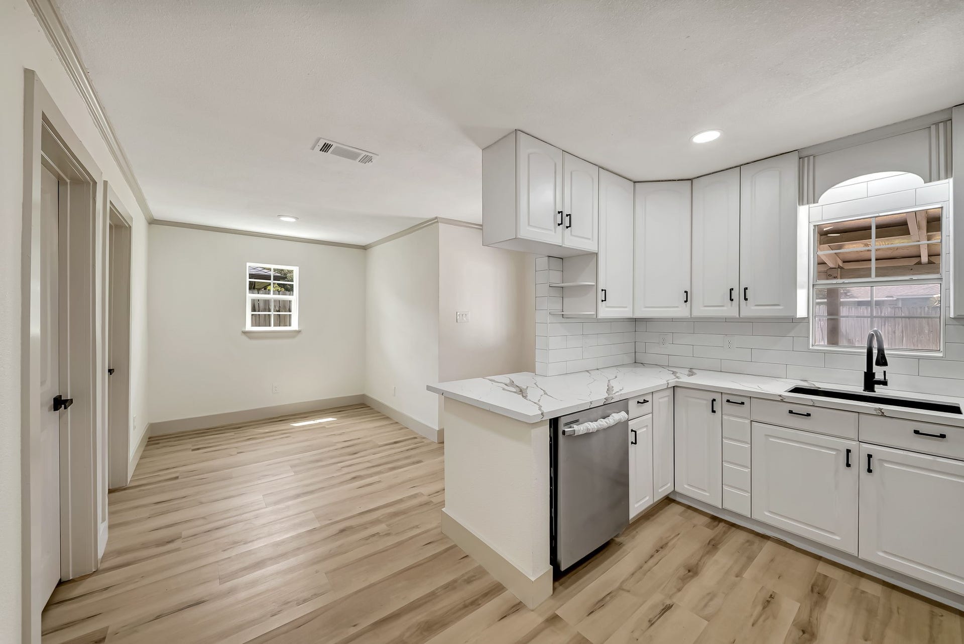 6638 Thornwall Street, Houston, TX 77092 Bright and airy kitchen with modern white cabinetry, sleek marble countertops, and stylish wood flooring, seamlessly flowing into the dinning area.