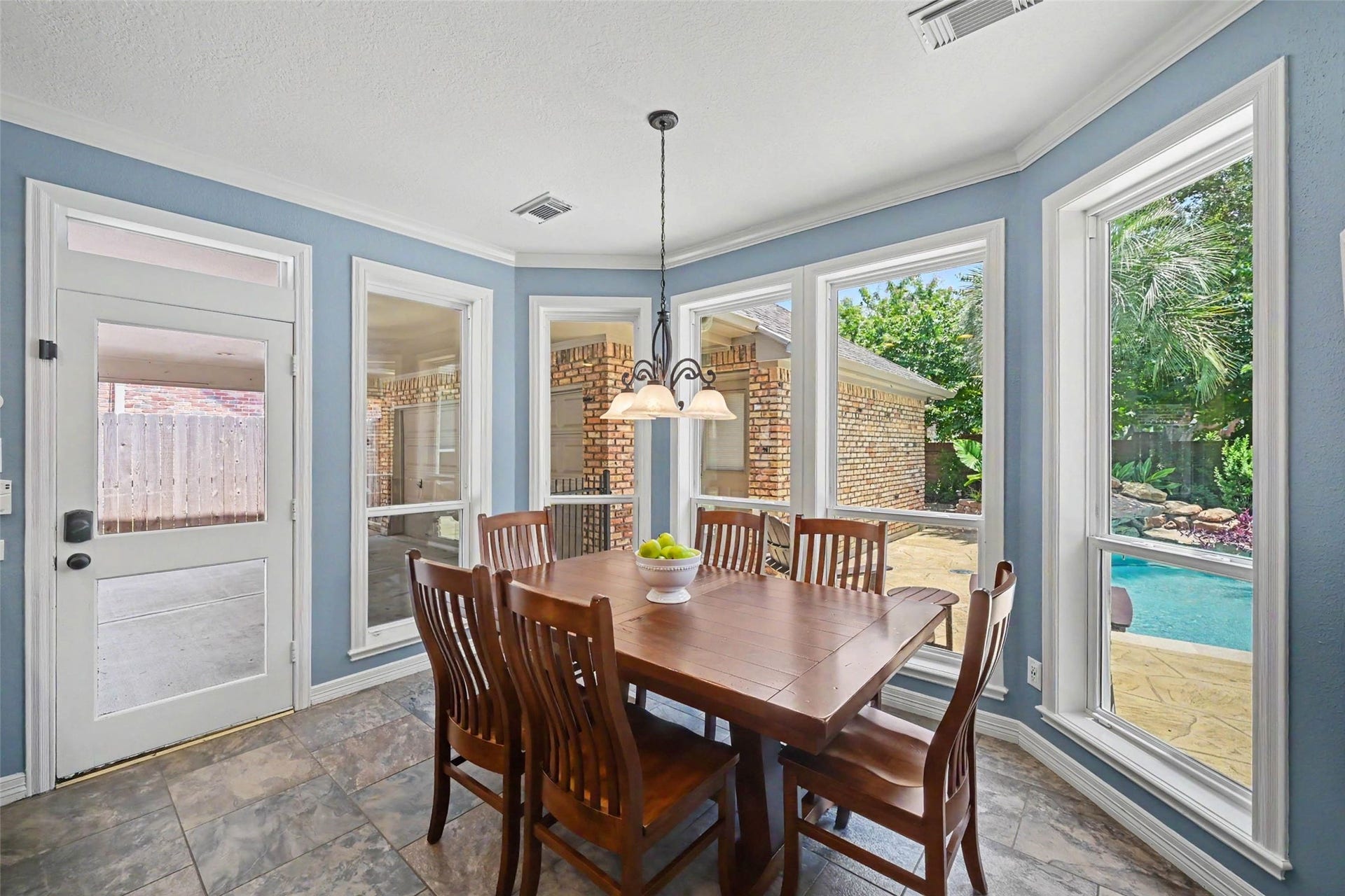 2907 Winding Shore Lane, Katy, TX 77450 Bright dining area with large windows offering views of the backyard pool, featuring elegant lighting, perfect for gatherings.