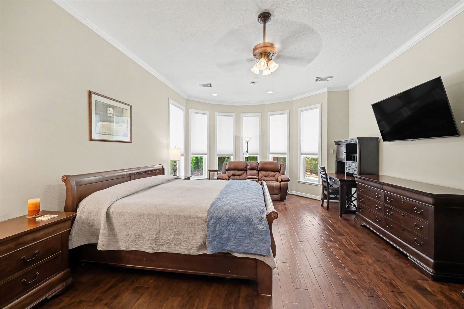 2907 Winding Shore Lane, Katy, TX 77450 Spacious primary bedroom with elegant hardwood flooring, featuring a cozy seating area by expansive bay windows for natural light.