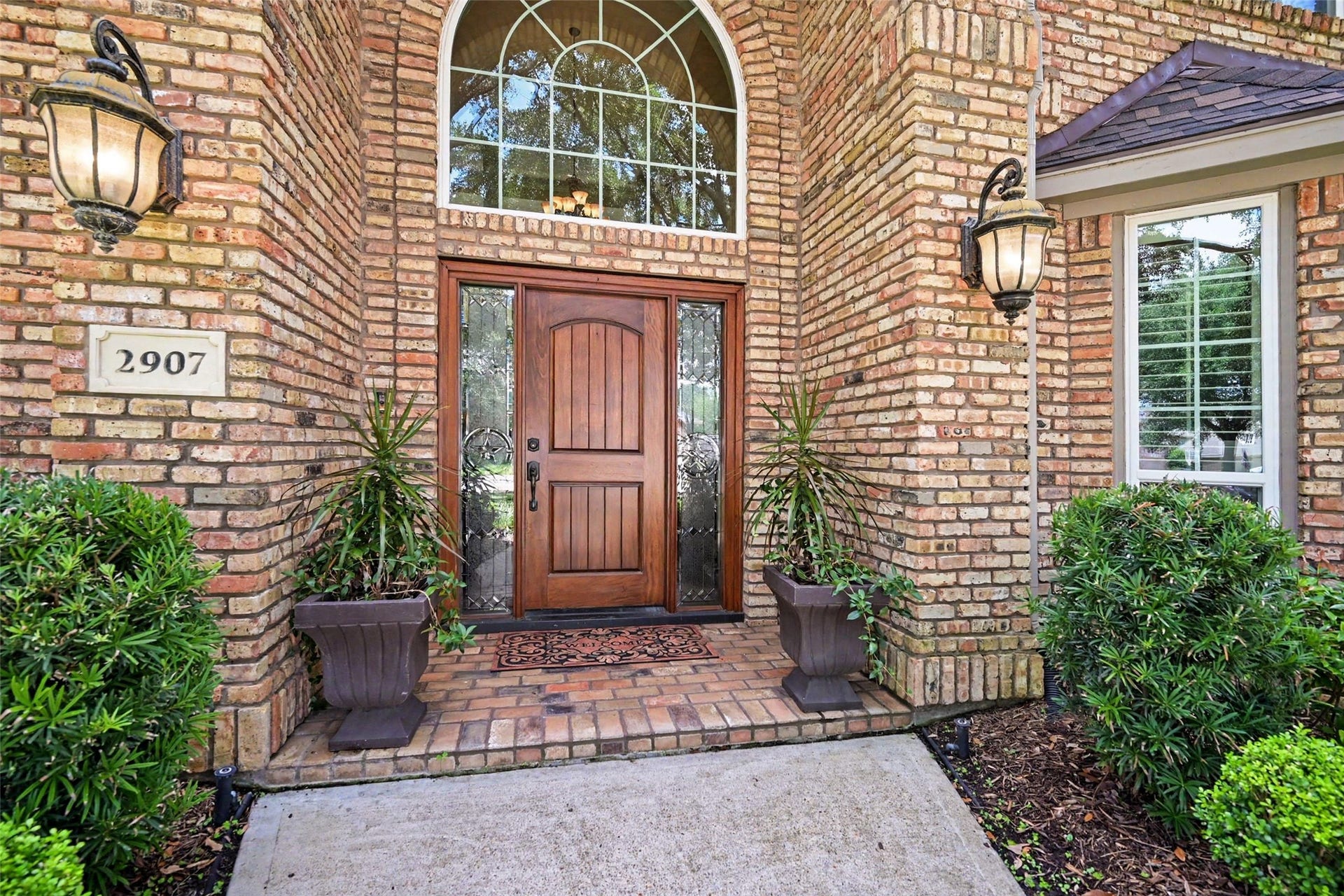 2907 Winding Shore Lane, Katy, TX 77450 Stately brick home with charming arched windows and a welcoming front pathway, surrounded by lush greenery and mature trees.
