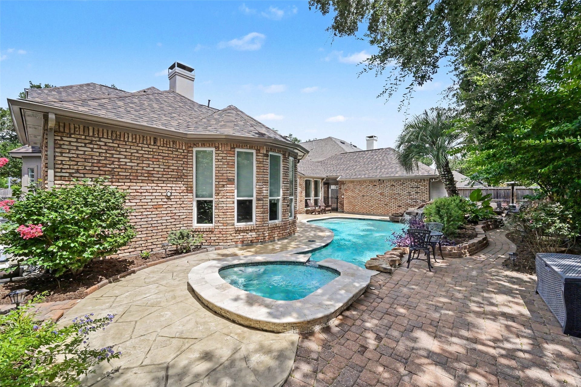2907 Winding Shore Lane, Katy, TX 77450 Charming backyard oasis featuring a sparkling pool and spa, surrounded by lush landscaping and a spacious patio perfect for outdoor entertaining.