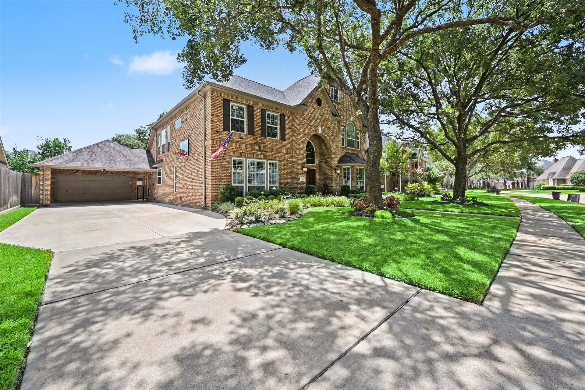 2907 Winding Shore Lane, Katy, TX 77450 Charming two-story brick home surrounded by lush greenery and mature trees, featuring a well-maintained front lawn and inviting sidewalk.