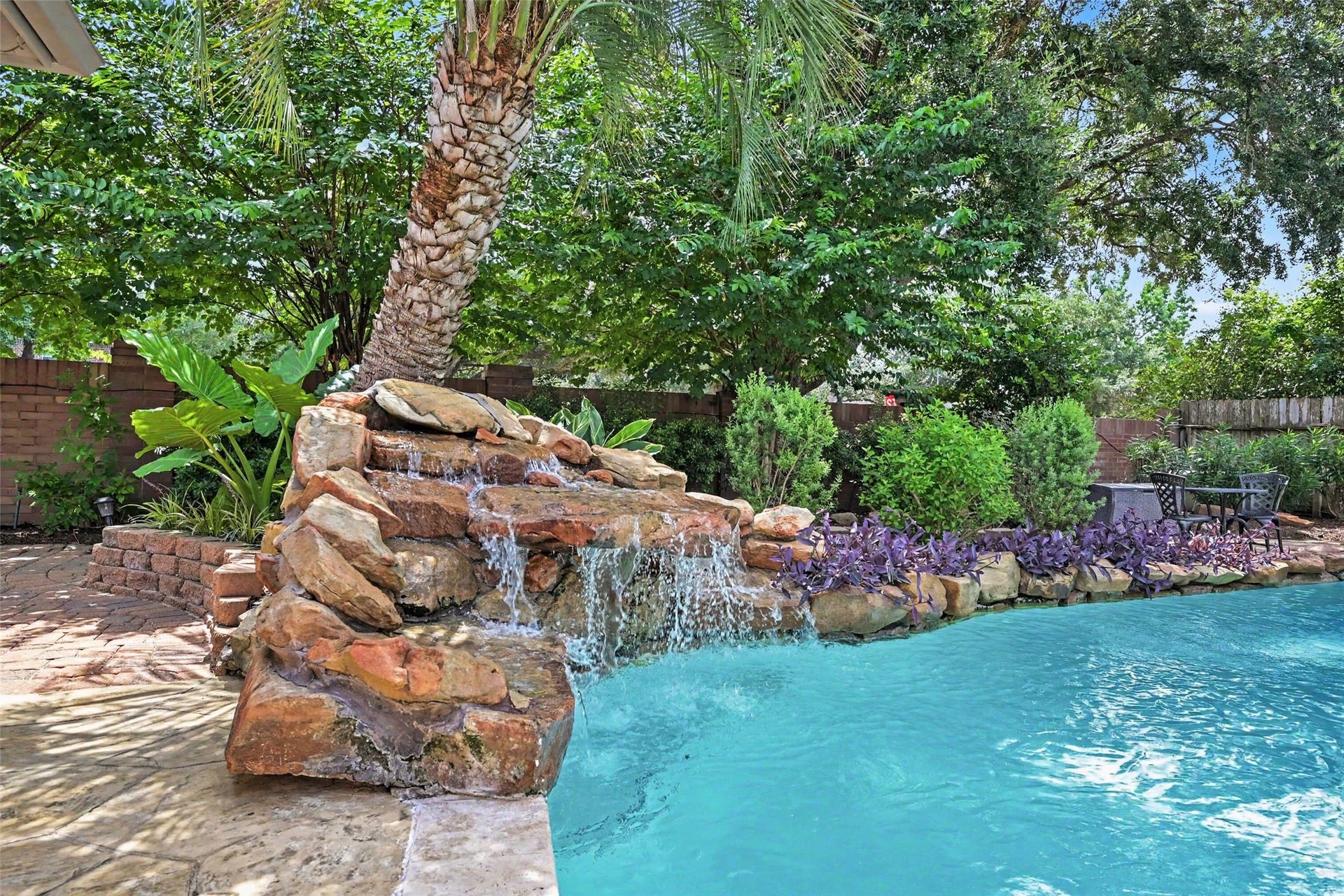2907 Winding Shore Lane, Katy, TX 77450 Backyard oasis with a sparkling pool, rock waterfall feature, and lush landscaping for ultimate relaxation and privacy.