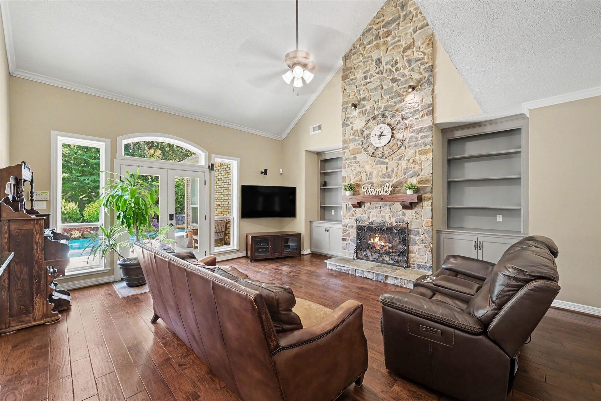 2907 Winding Shore Lane, Katy, TX 77450 Another view of the spacious family room highlights the open-concept layout, custom built-ins, cozy fireplace, and expansive windows overlooking the sparkling backyard pool, creating a bright and inviting gathering space.