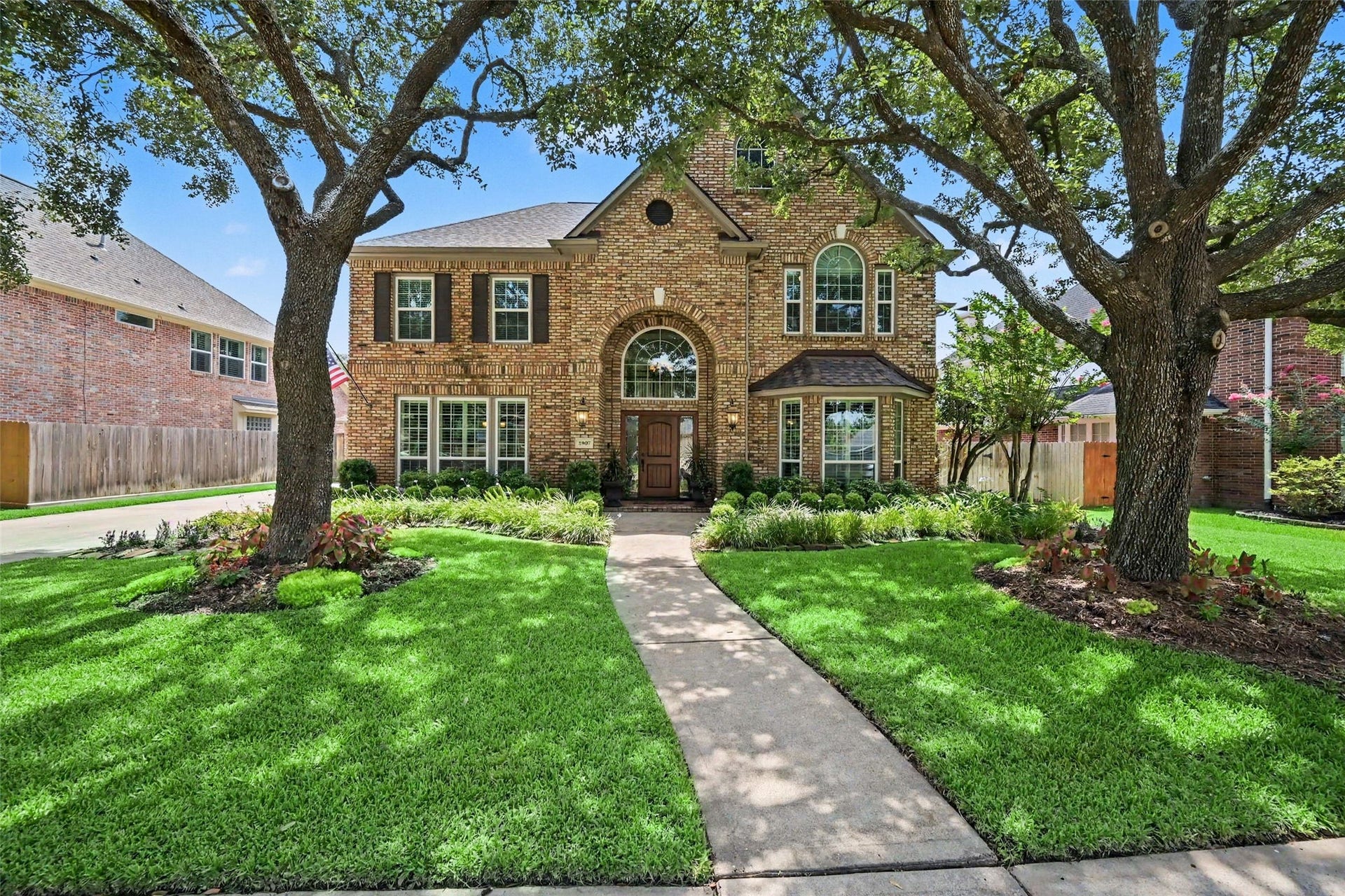 2907 Winding Shore Lane, Katy, TX 77450 Stunning brick home with charming architectural details, framed by mature trees and lush landscaping, offering a warm and inviting curb appeal.