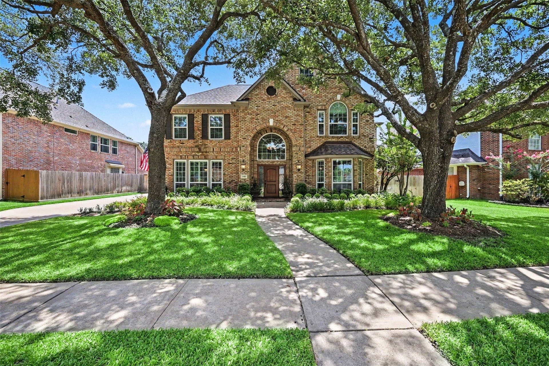 2907 Winding Shore Lane, Katy, TX 77450 Charming brick home with a welcoming arched entryway, framed by mature trees and lush landscaping, offers great curb appeal.