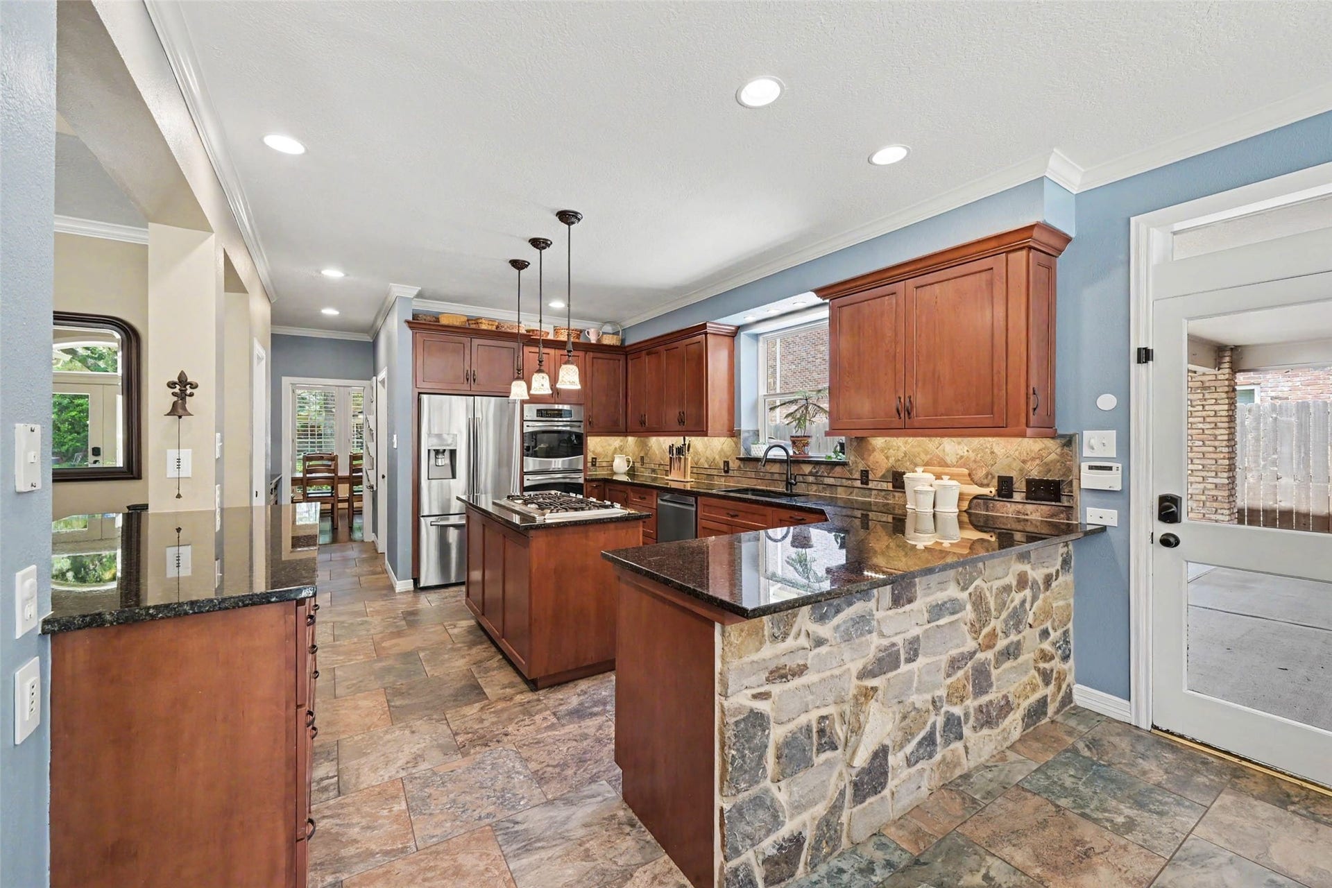 2907 Winding Shore Lane, Katy, TX 77450 The well-appointed kitchen features granite countertops, custom cabinetry with abundant storage, double ovens, and a large walk-in pantry. Enjoy beautiful views of the backyard pool while preparing meals.