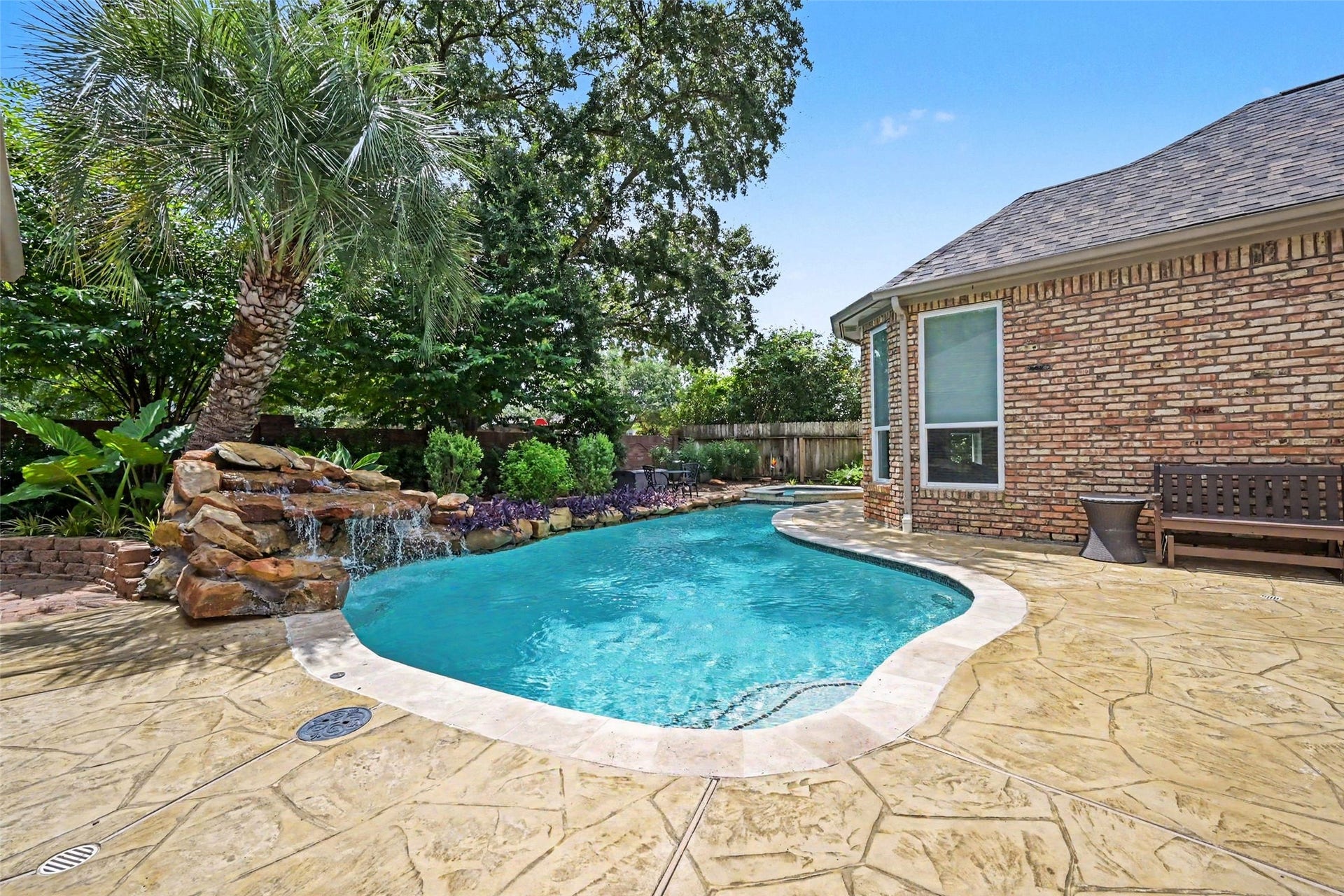 2907 Winding Shore Lane, Katy, TX 77450 Experience serene outdoor living with this inviting backyard oasis, featuring a sparkling pool with a waterfall, lush landscaping, and a spacious patio perfect for relaxation.
