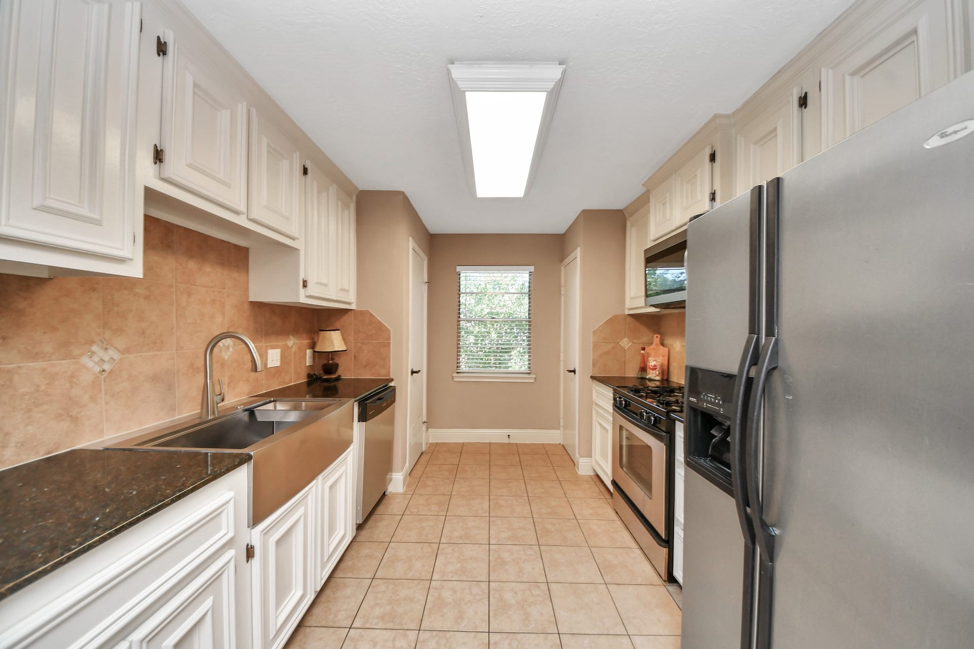 935 Grand Junction Drive, Katy, TX 77450 Designed to maximize functionality, this well-appointed galley kitchen offers generous cabinetry and countertop space along both sides of the room. The thoughtful arrangement places the stainless steel farmhouse-style sink and dishwasher opposite the gas range, built-in microwave, and side-by-side refrigerator, creating convenient work areas for cooking and cleanup.